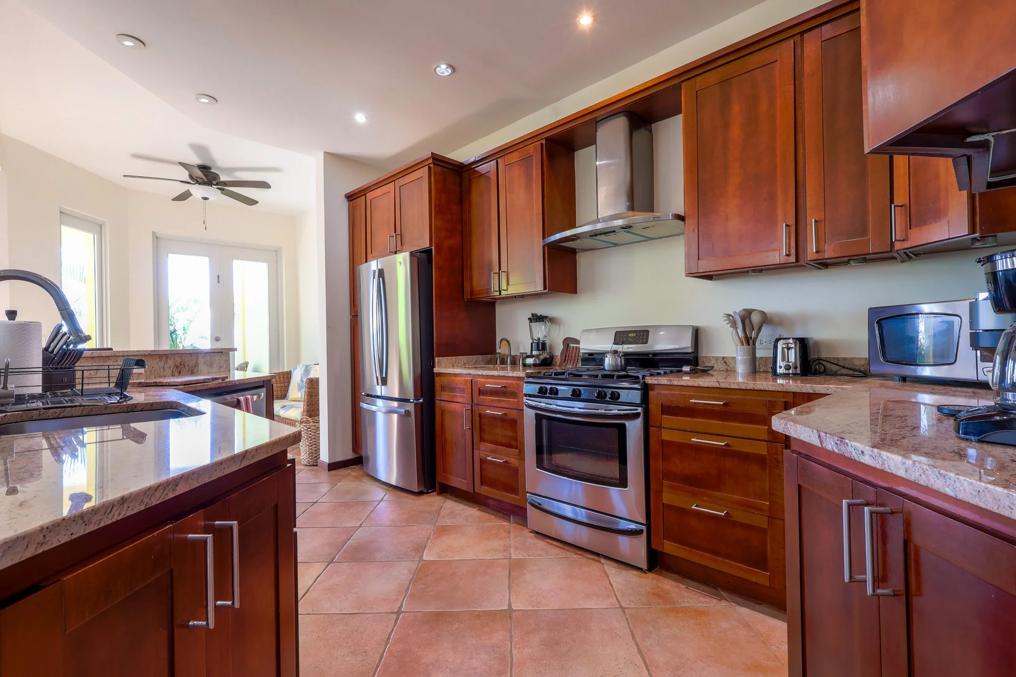 Kitchen with wooden cabinets, stainless steel appliances, tile floor, and bright natural light.