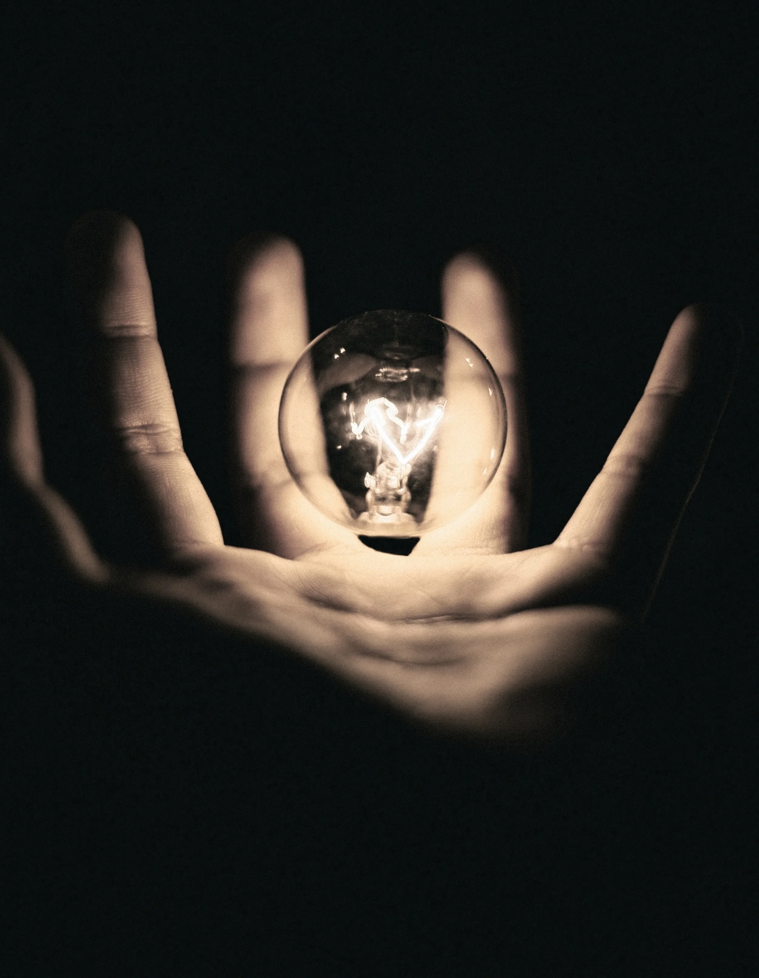 Hand holding a lit lightbulb — bright ideas and innovative safety solutions