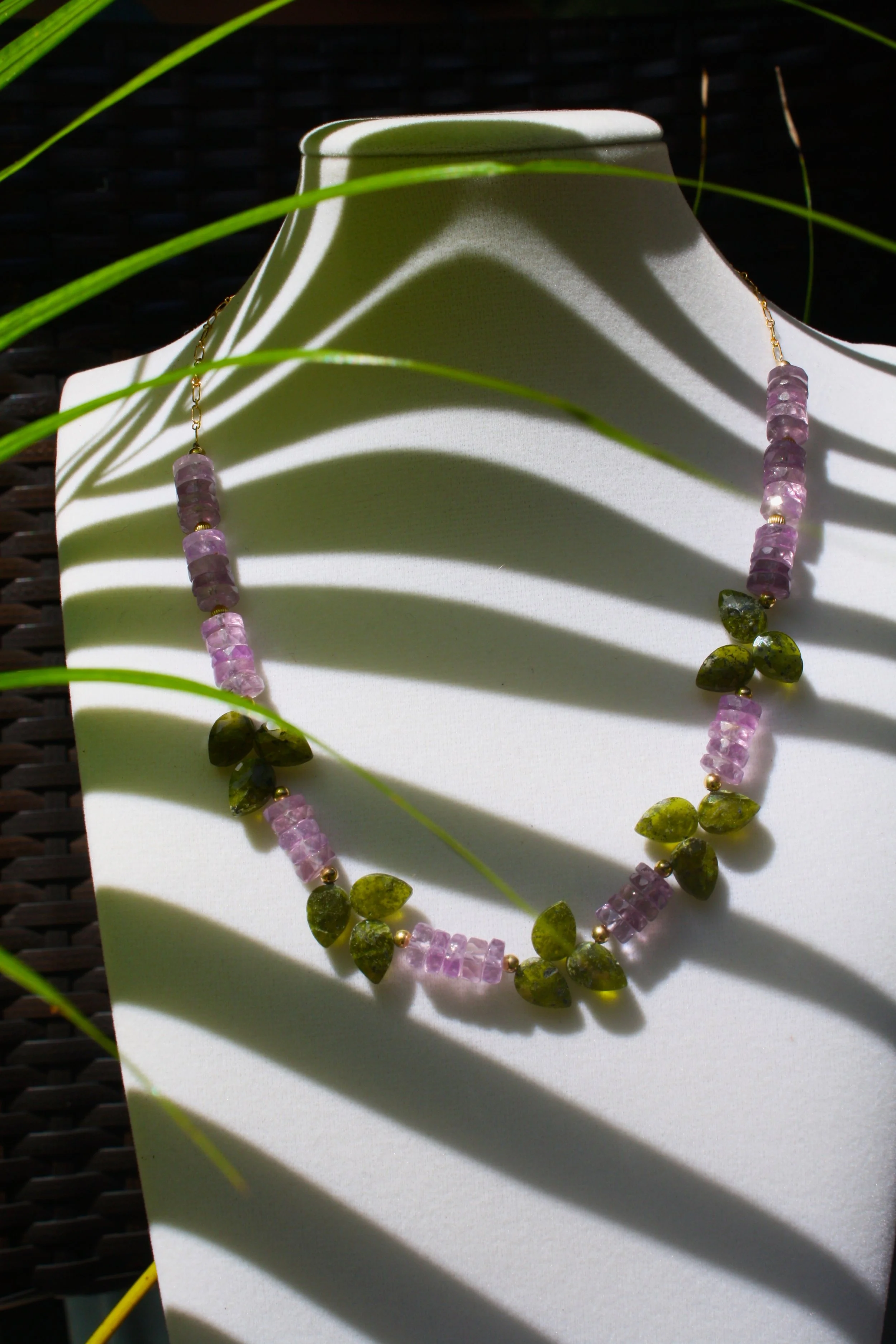 amethyst and peridot gemstone necklace displayed on jewelry stand, colorful luxury Hawaiian jewelry. spring collection
