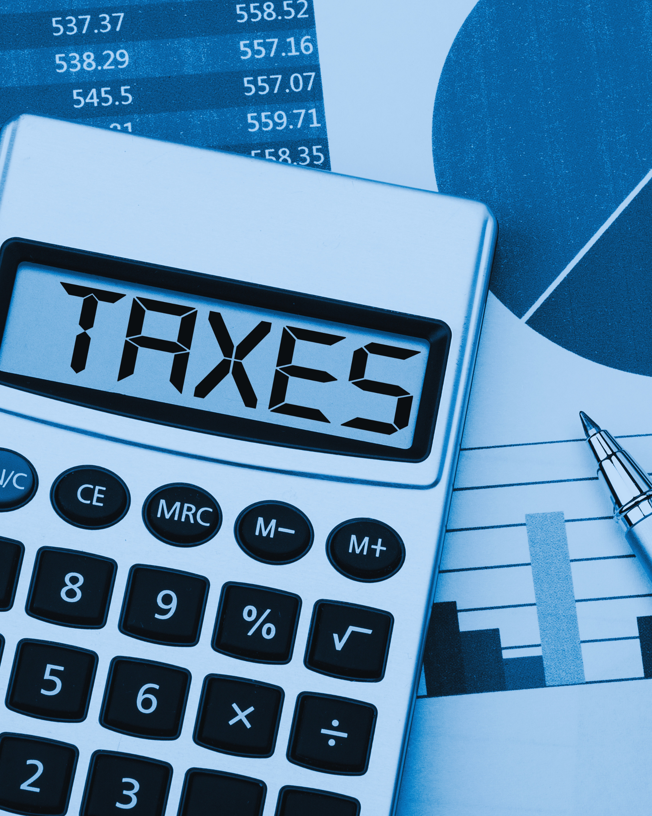 Close-up of a calculator displaying 'TAXES' and a pen, with financial documents and a paper with graphs and numerical data in the background.