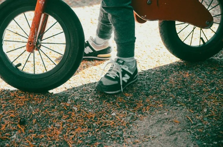 child's feet in sneakers seated on a scooter
