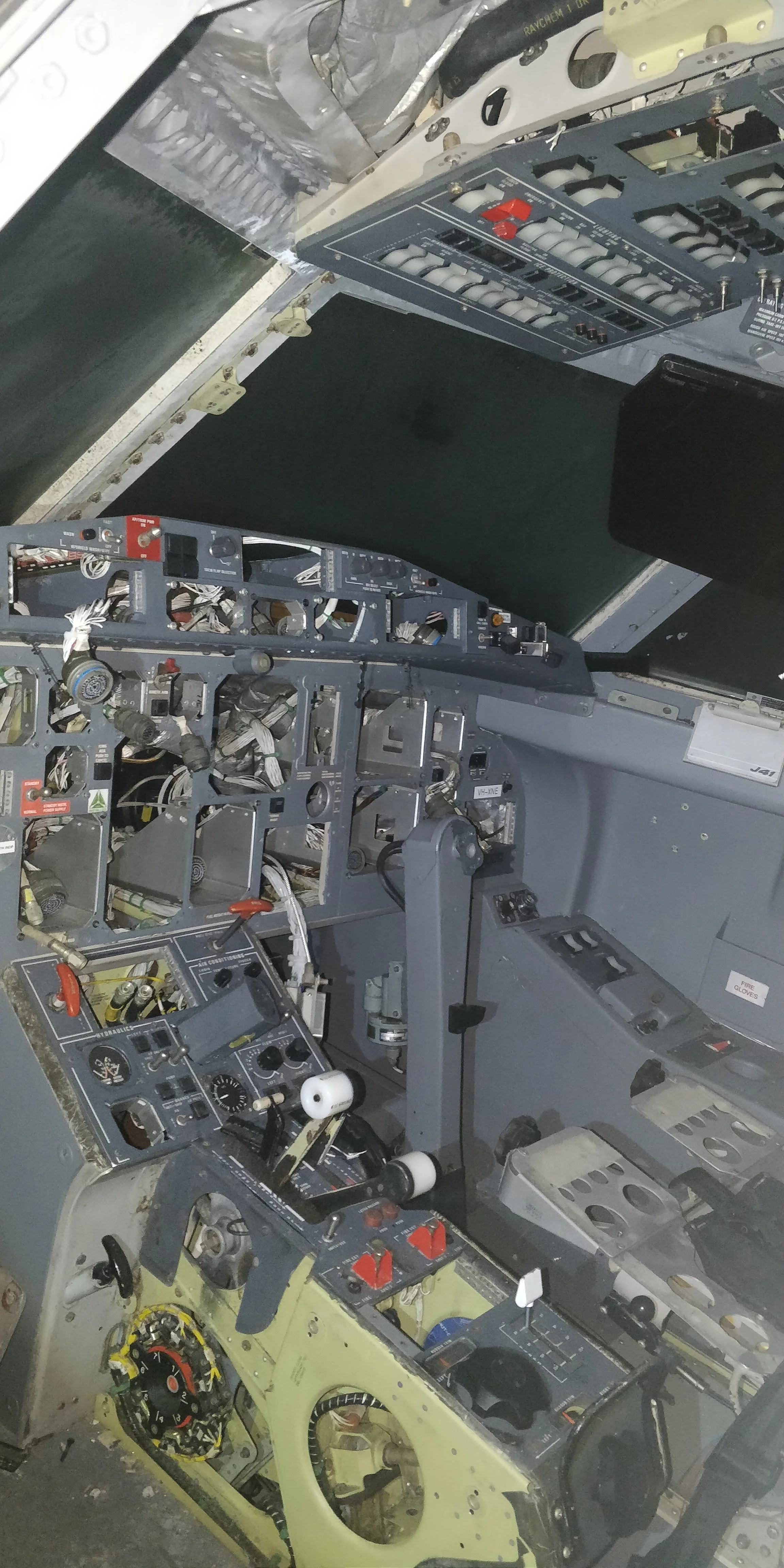 Interior view of an aircraft cockpit (Jetstream 41) with exposed instrumentation, wiring, and controls, including fire gloves storage area.