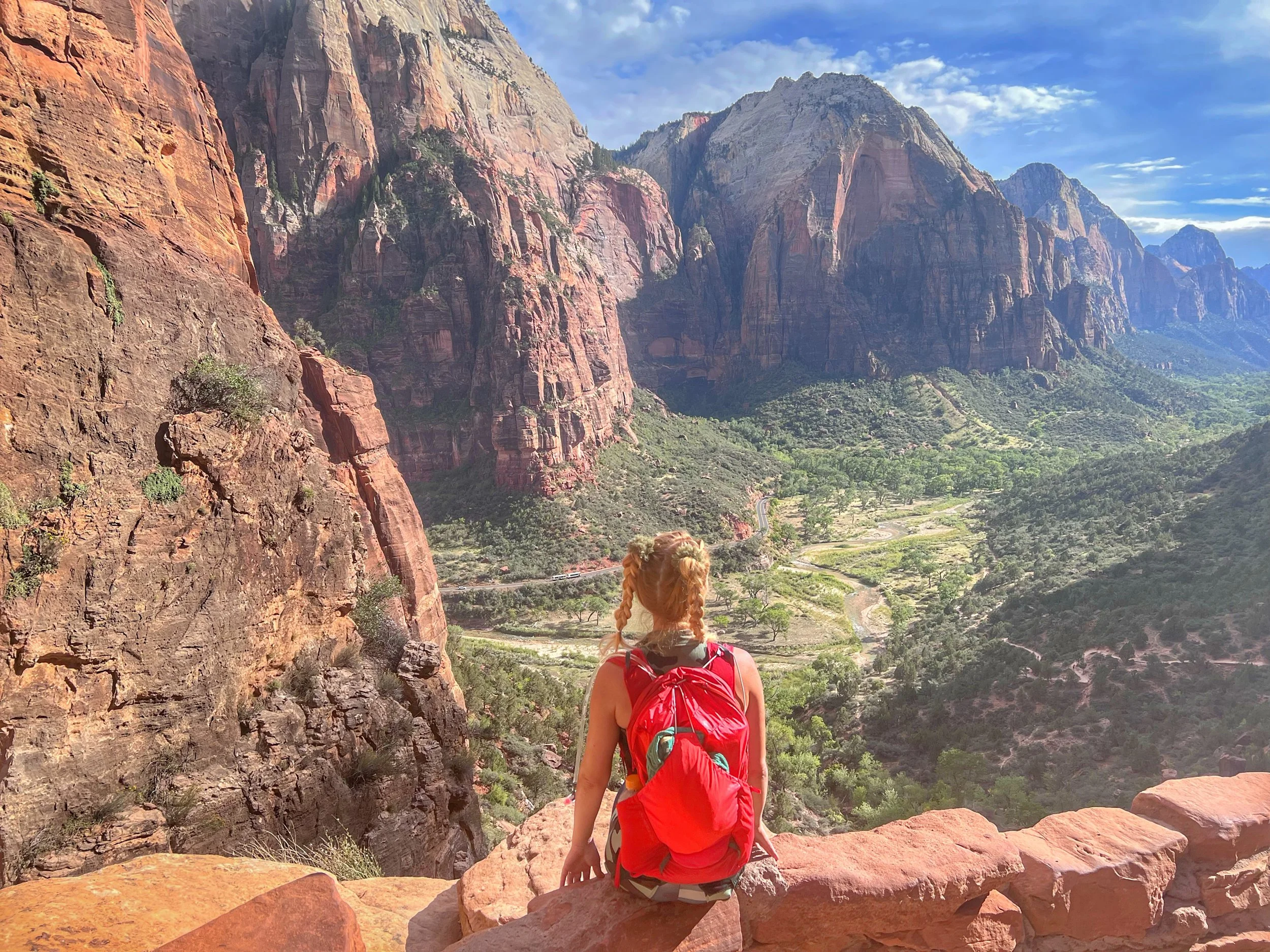 Hiker overlooking Zion National Park canyon and red rock cliffs in Utah