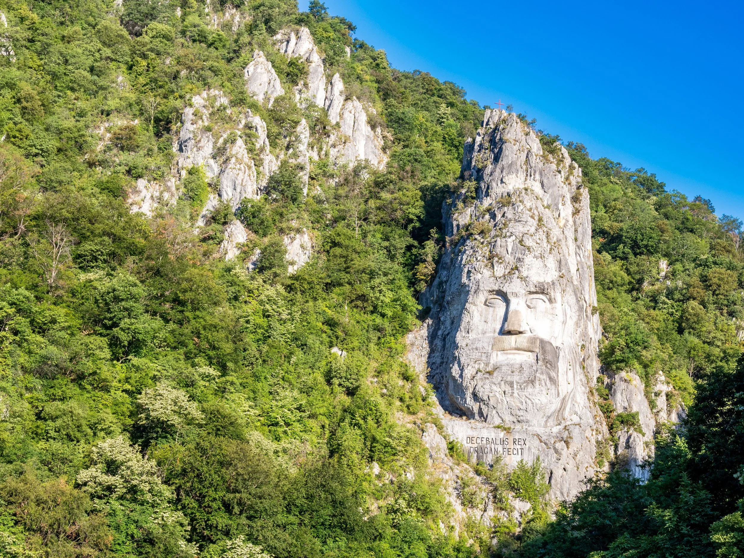 Massive rock sculpture of King Decebalus carved into cliffs along the Danube River in Romania.