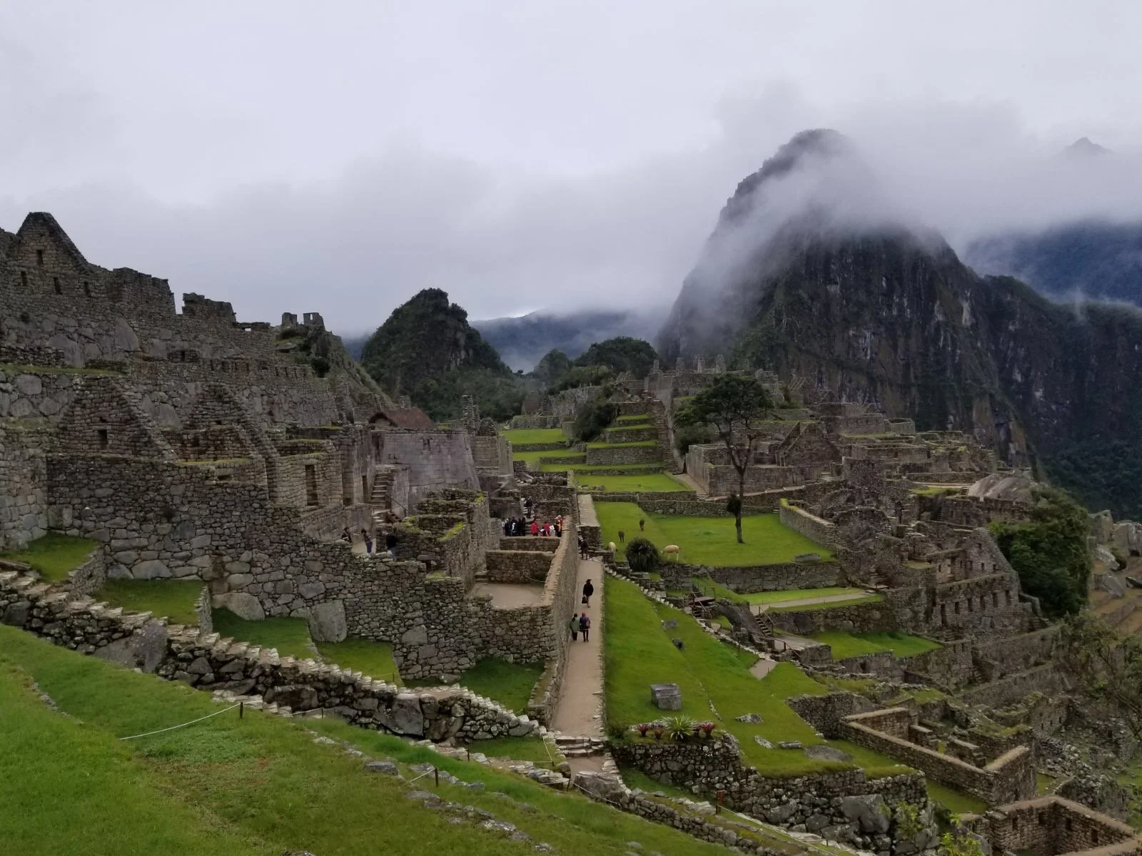 Machu Picchu ancient Inca citadel in Peru surrounded by misty Andes mountains, with stone terraces, ruins, and Huayna Picchu peak rising above the Sacred Valley.