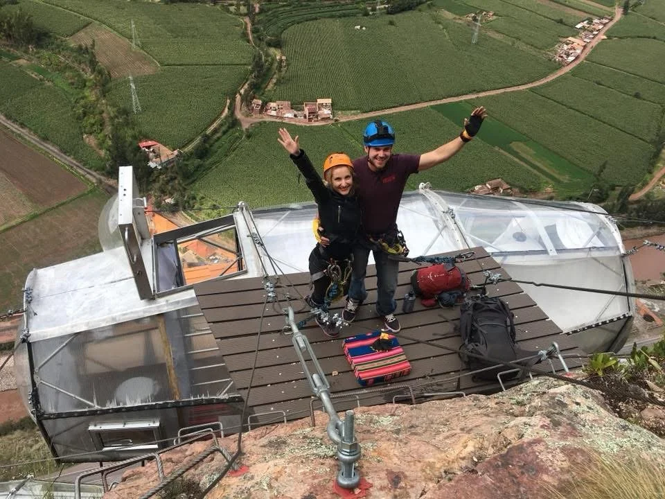 Couple standing on a platform above Skylodge Adventure Suites glass capsules overlooking the Sacred Valley near Cusco, Peru.