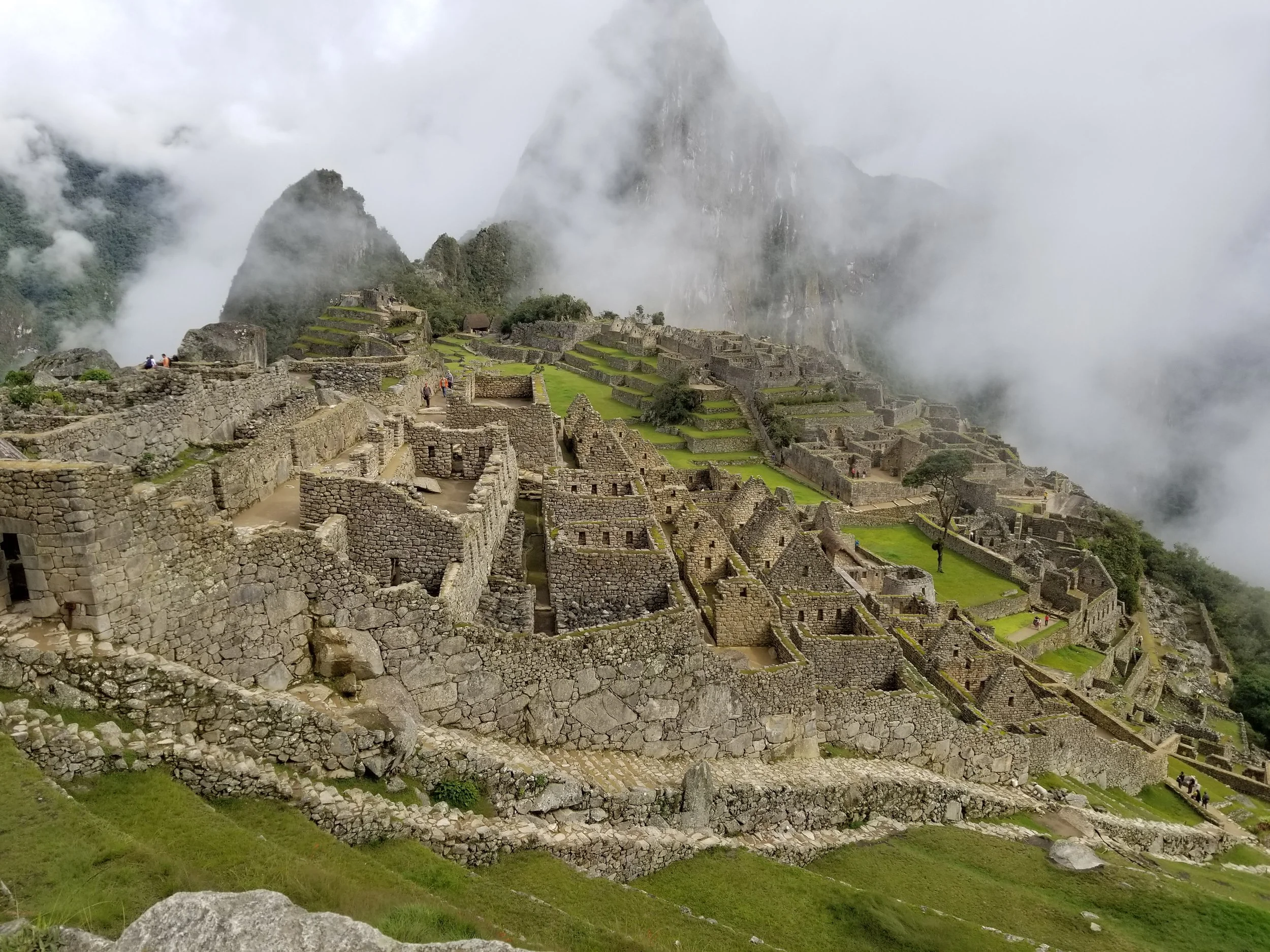 The ancient stone terraces and temples of Machu Picchu emerging through the mist of the Peruvian Andes.