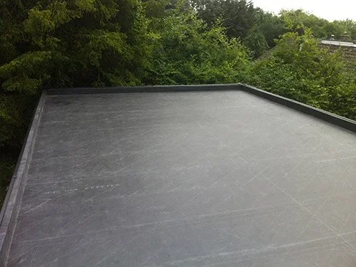 Flat black rooftop with green trees in the background