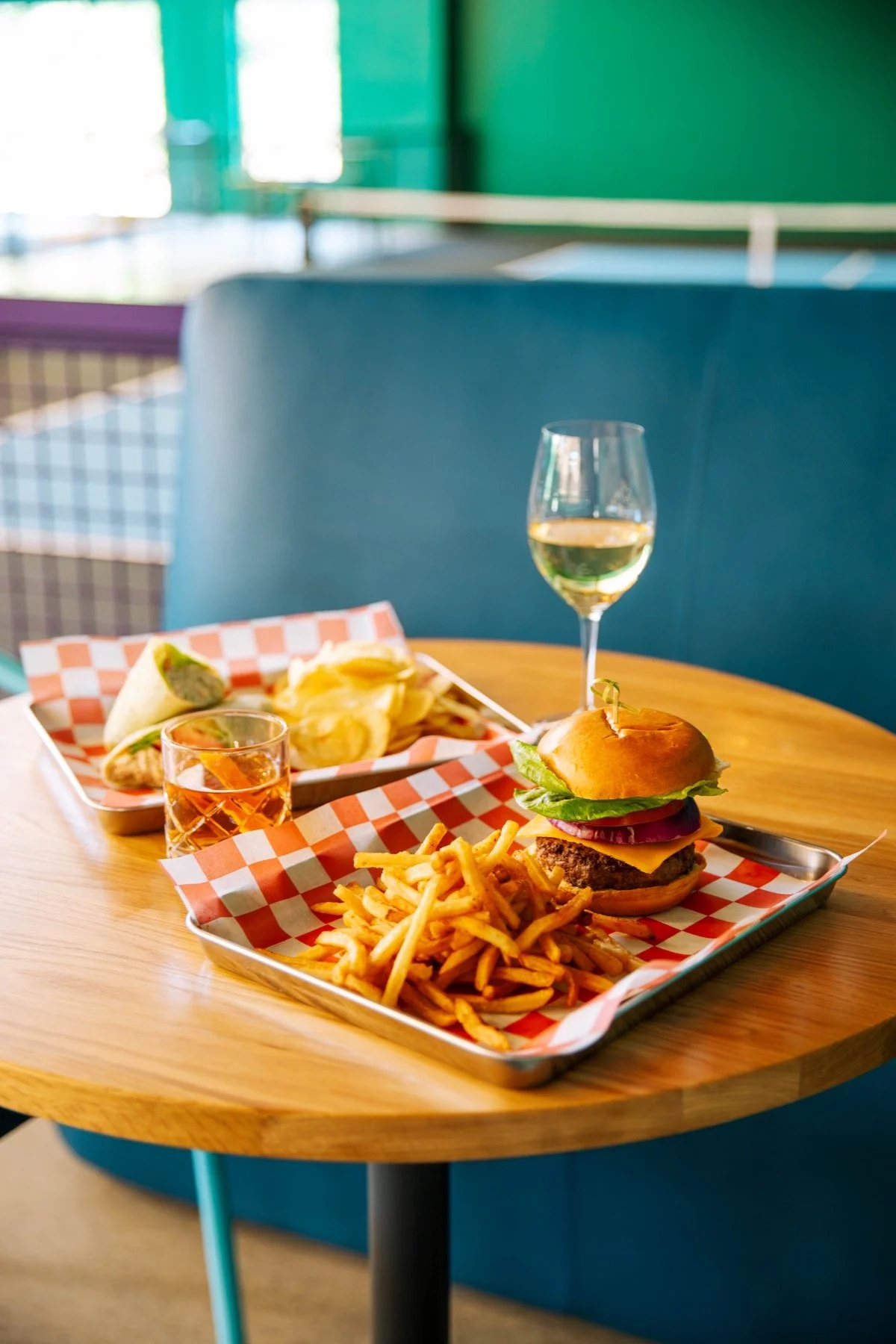 Tray with cheeseburger, French fries, and condiments on a wooden table in a restaurant.