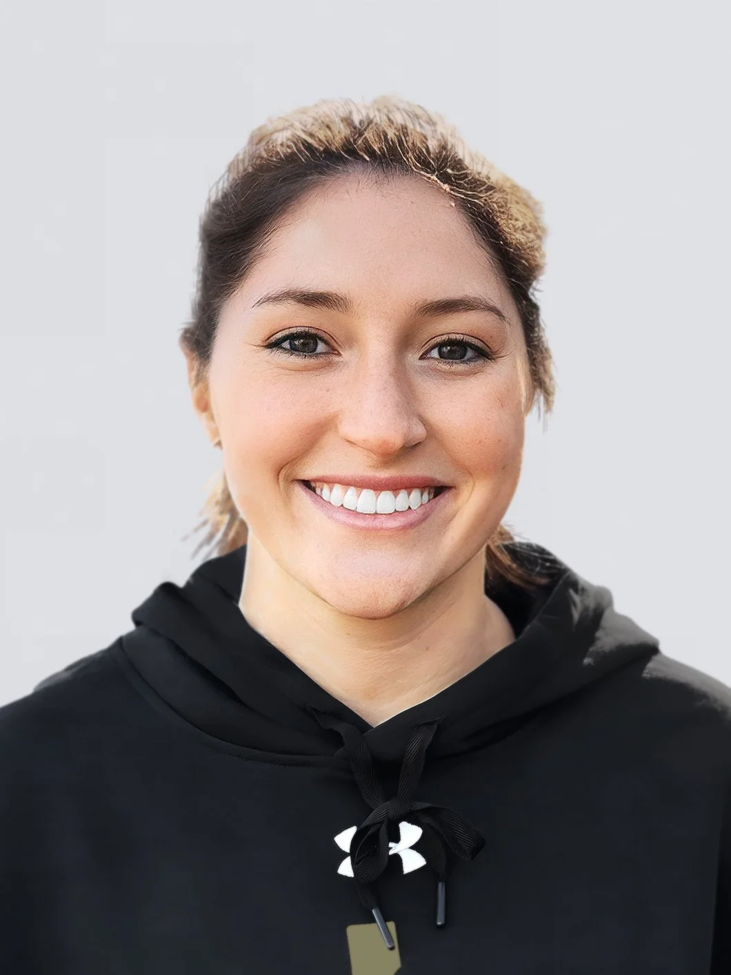 Smiling person wearing a black hoodie with a logo, against a plain background.