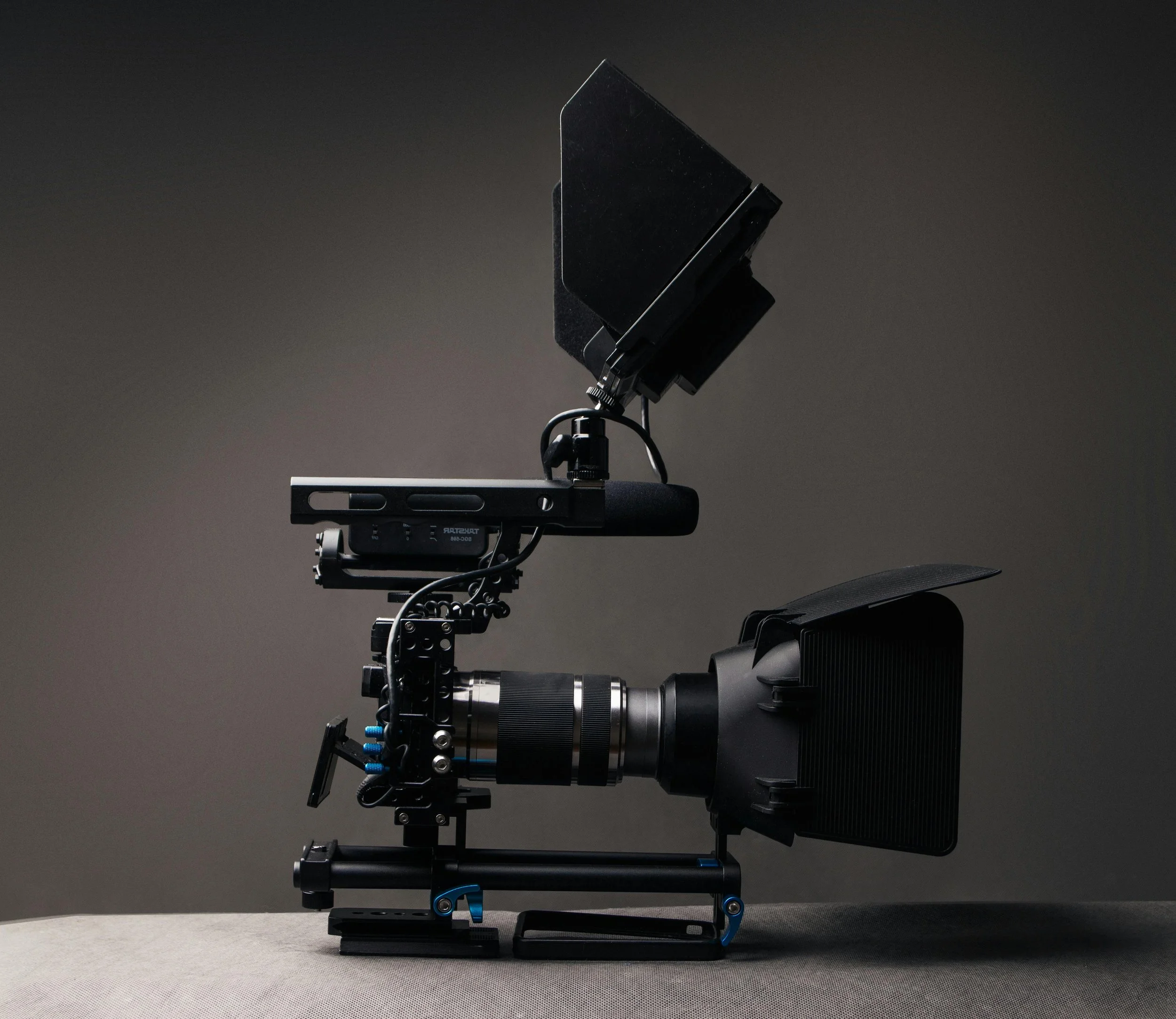 Professional camera mounted on a stabilizing rig with a matte box and monitor, set against a dark background.