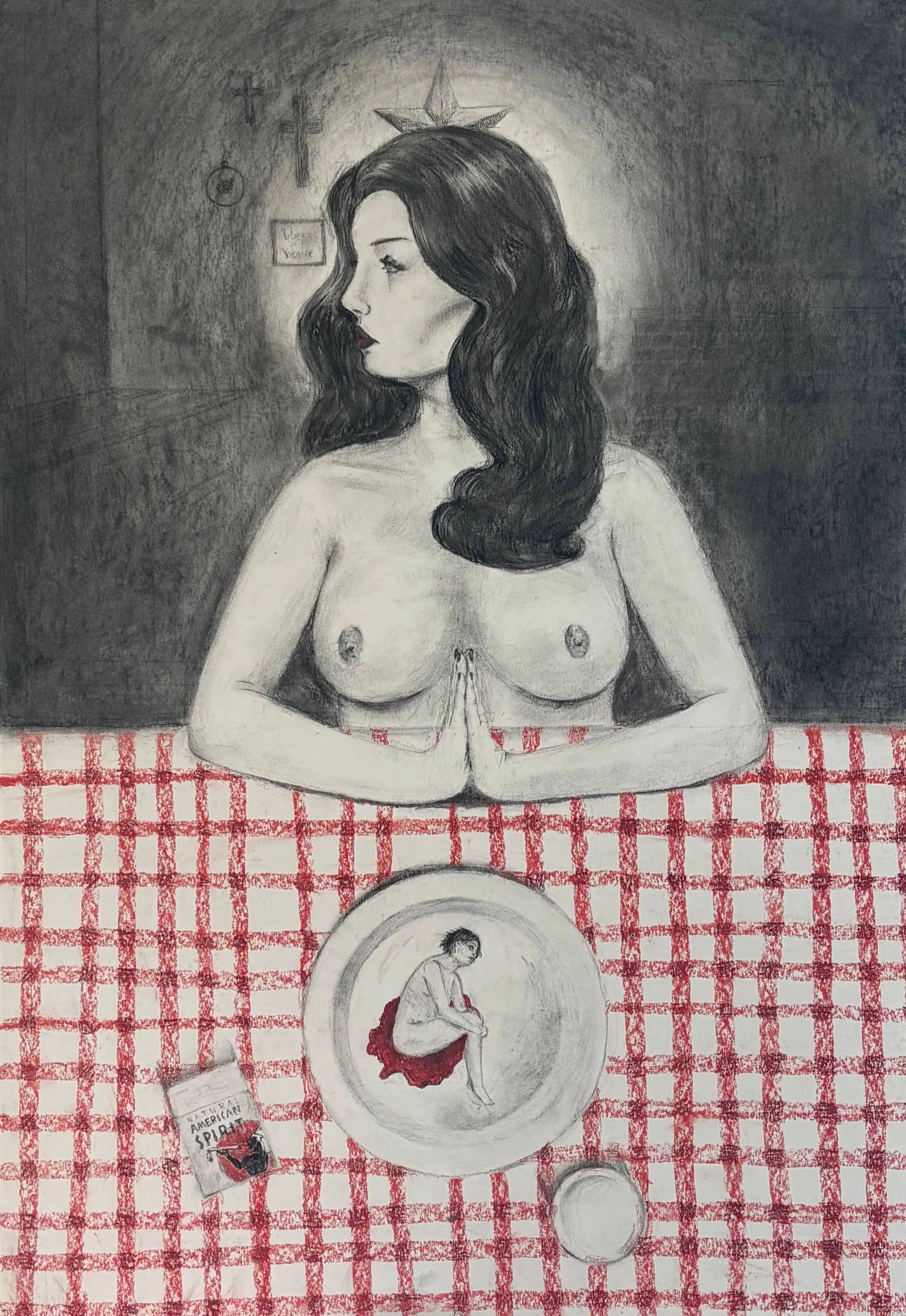 A topless woman sits at a table with hands pressed together; a plate in front of her shows a small curled figure, with a red-checked tablecloth and religious symbols in the background.