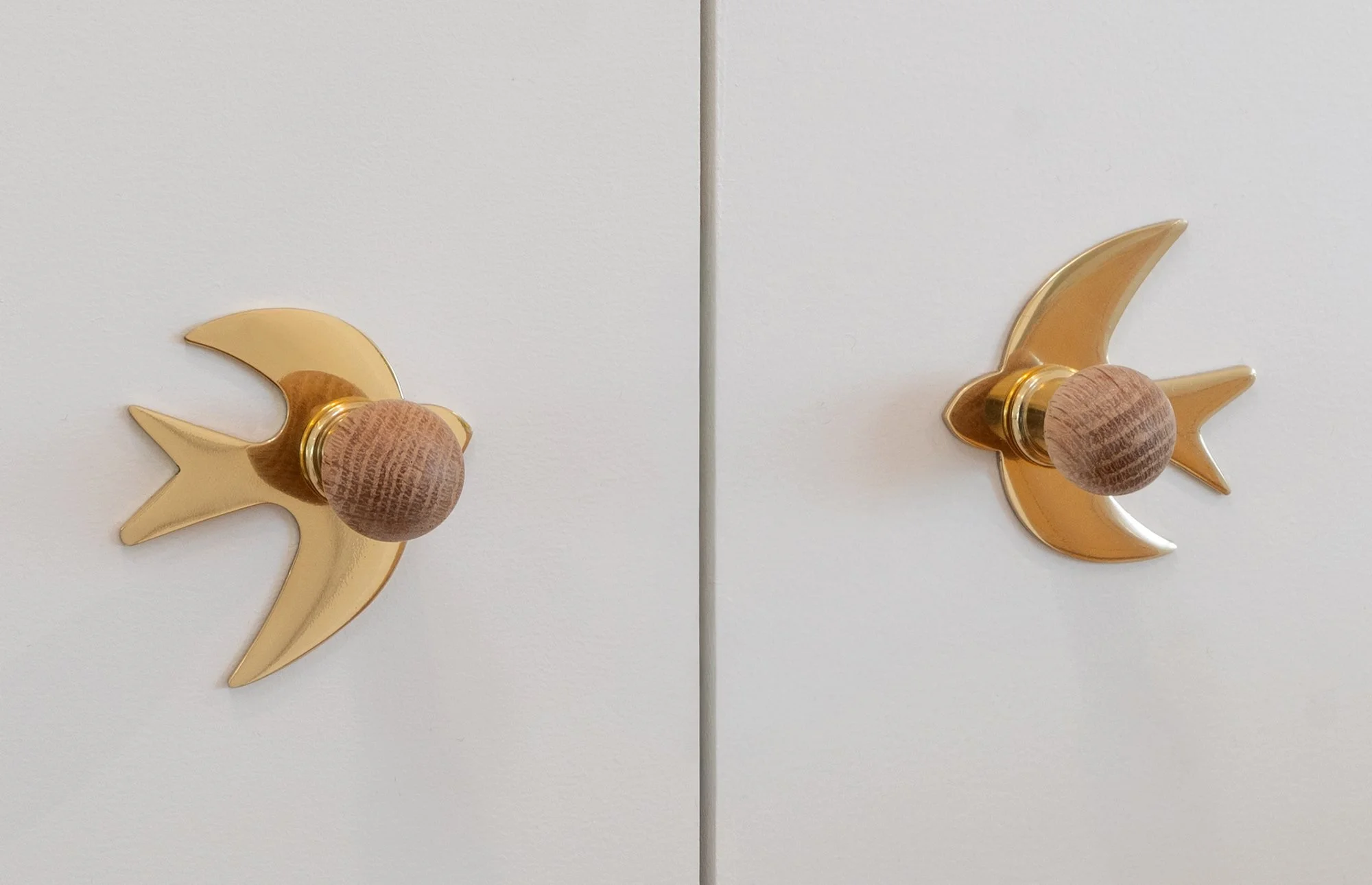 Two white cabinet doors with gold fairy-themed door knobs featuring a crescent moon and star design, each with a round wooden handle in the center.