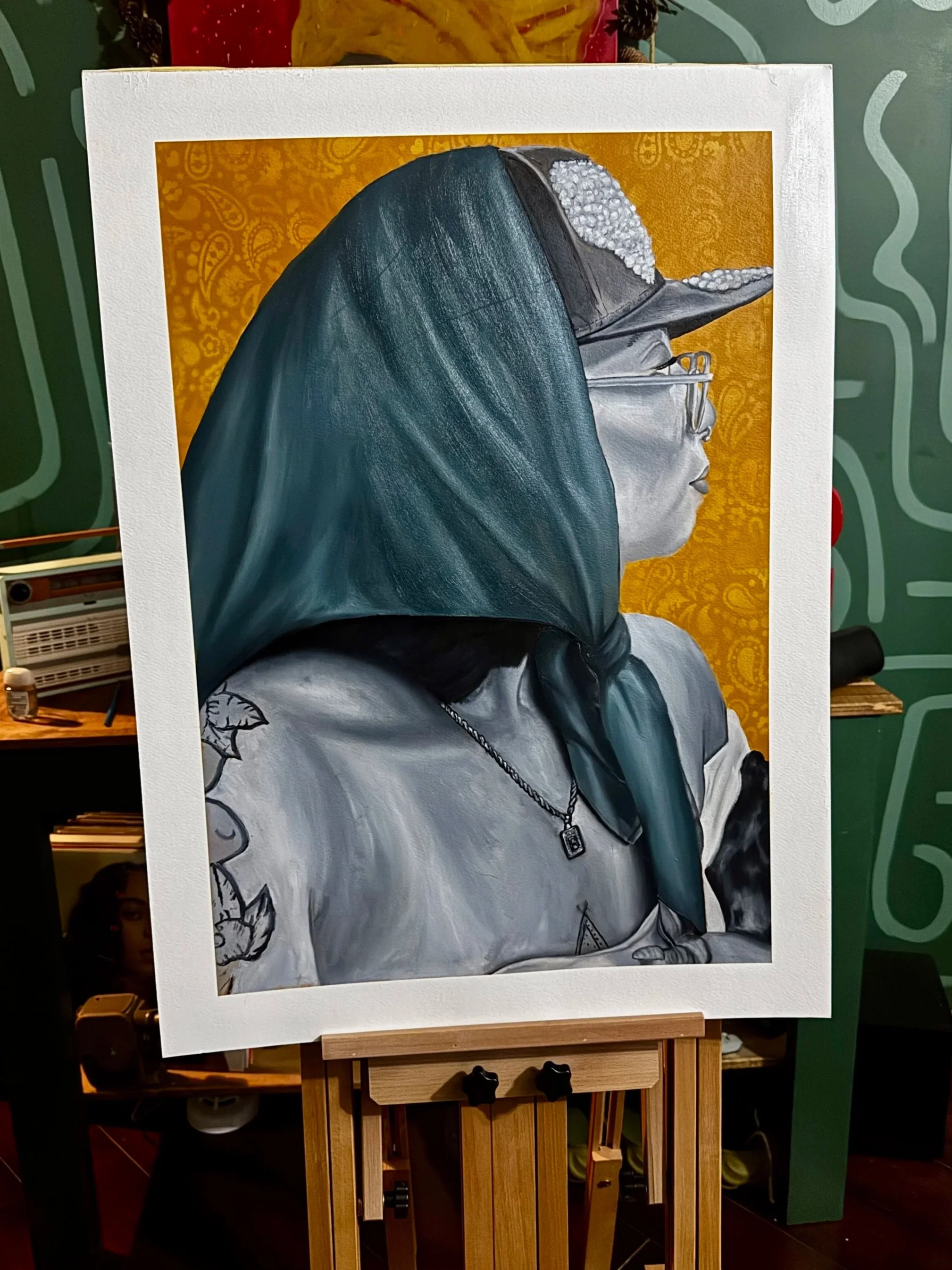 A detailed painting of a woman in profile, wearing a cap and glasses, with a large blue-green scarf covering her head and shoulders, against a yellow patterned background.
