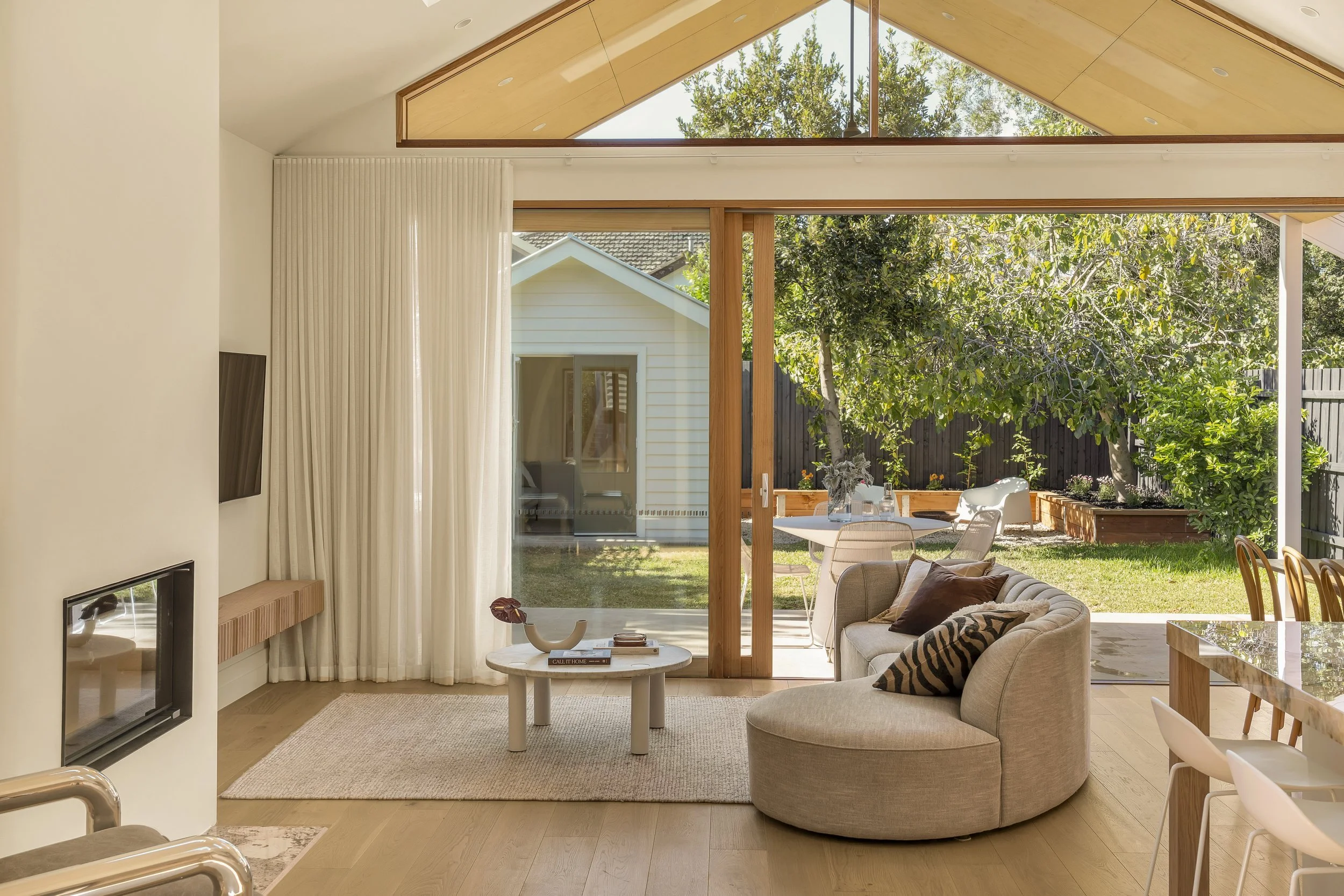Living room with large glass sliding door opening to a backyard with trees and outdoor seating.
