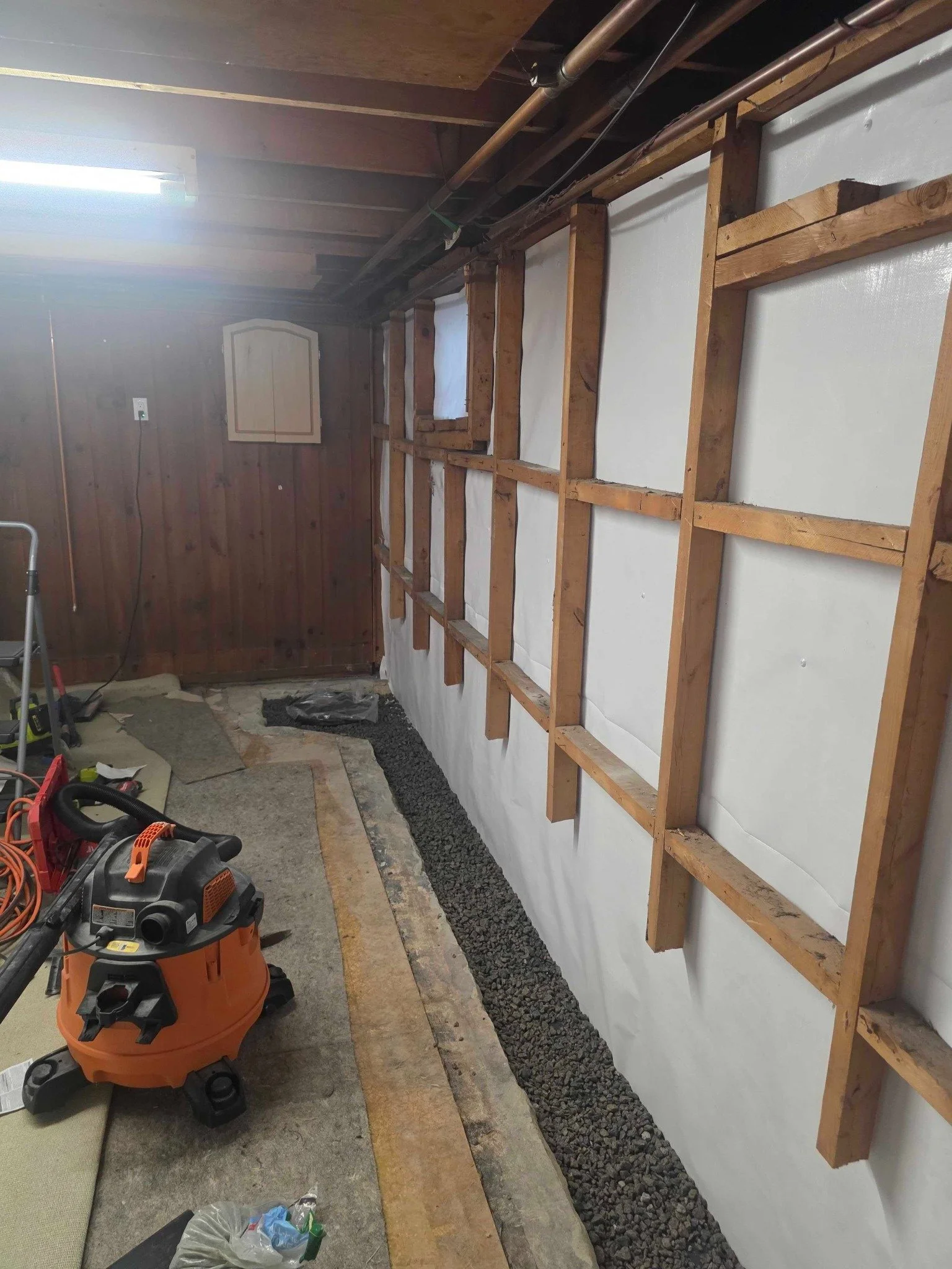 Partial perimeter drain installation along the opened slab edge in a finished Manchester basement.