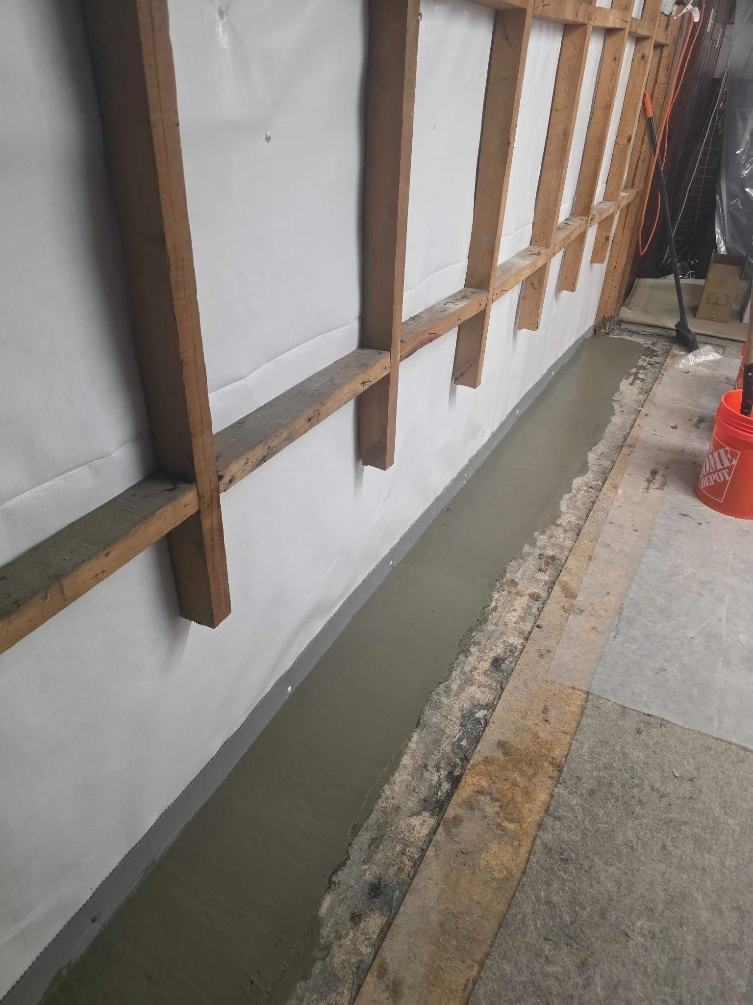 New concrete finished along the basement perimeter after drain installation.