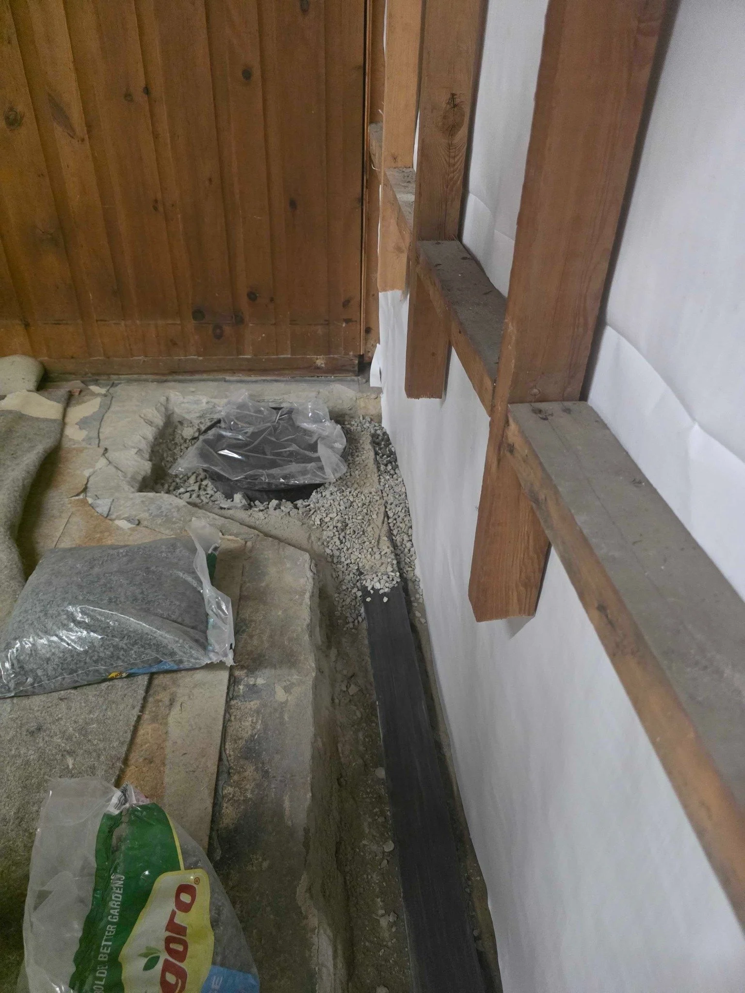 Sump basin excavation with drainage stone during partial perimeter drain installation in Manchester, NH.