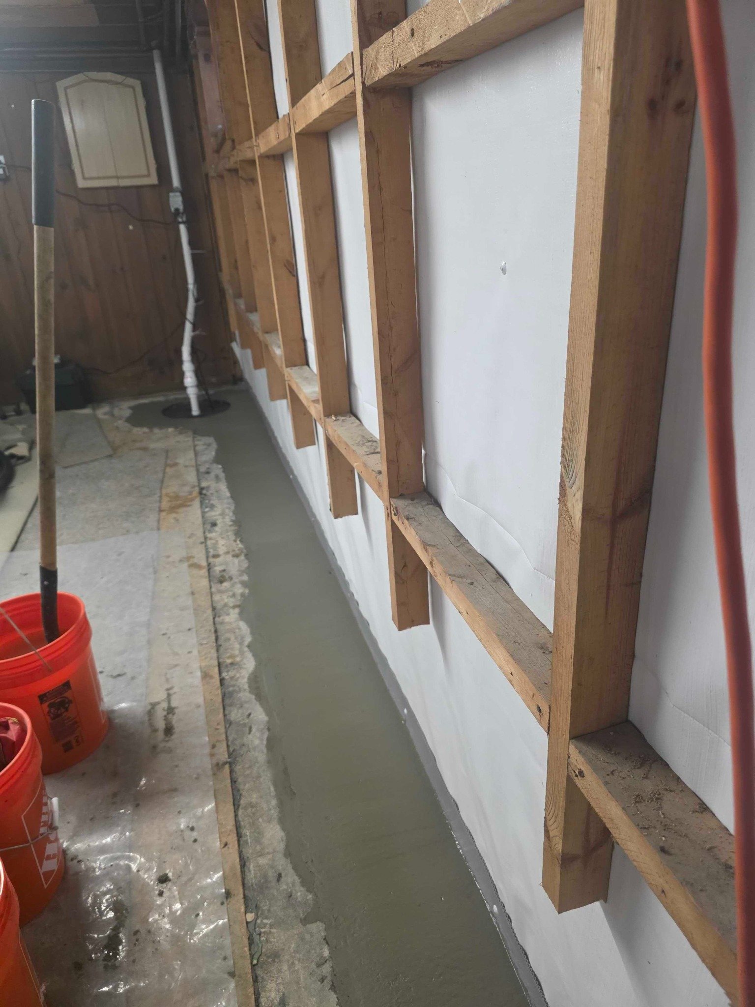 Restored concrete slab edge beneath exposed basement framing in Manchester, NH.