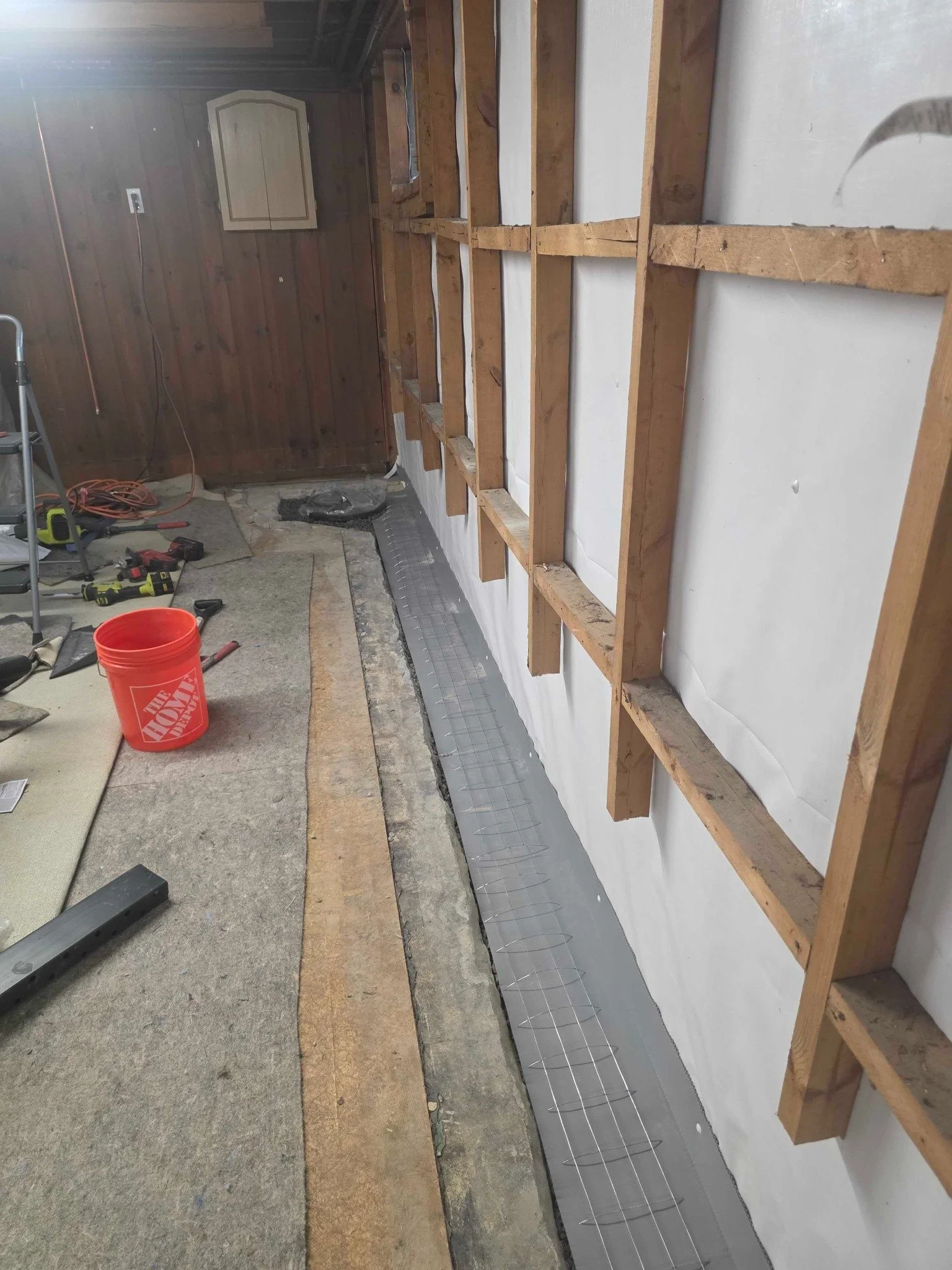 Long section of exposed framing and slab-edge drainage trench before concrete restoration.