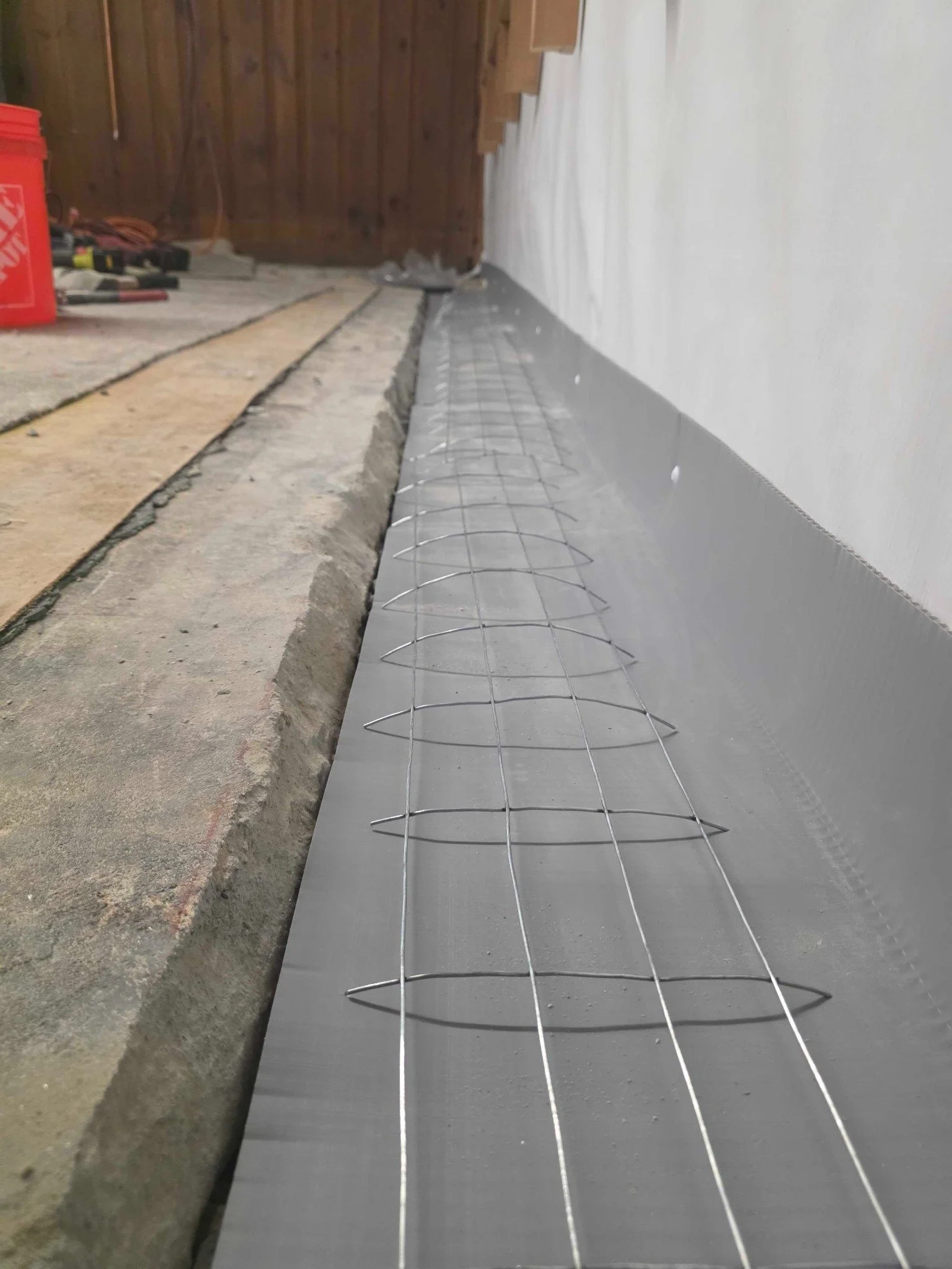 Prepared basement drainage trench with reinforcing mesh before new concrete was placed.