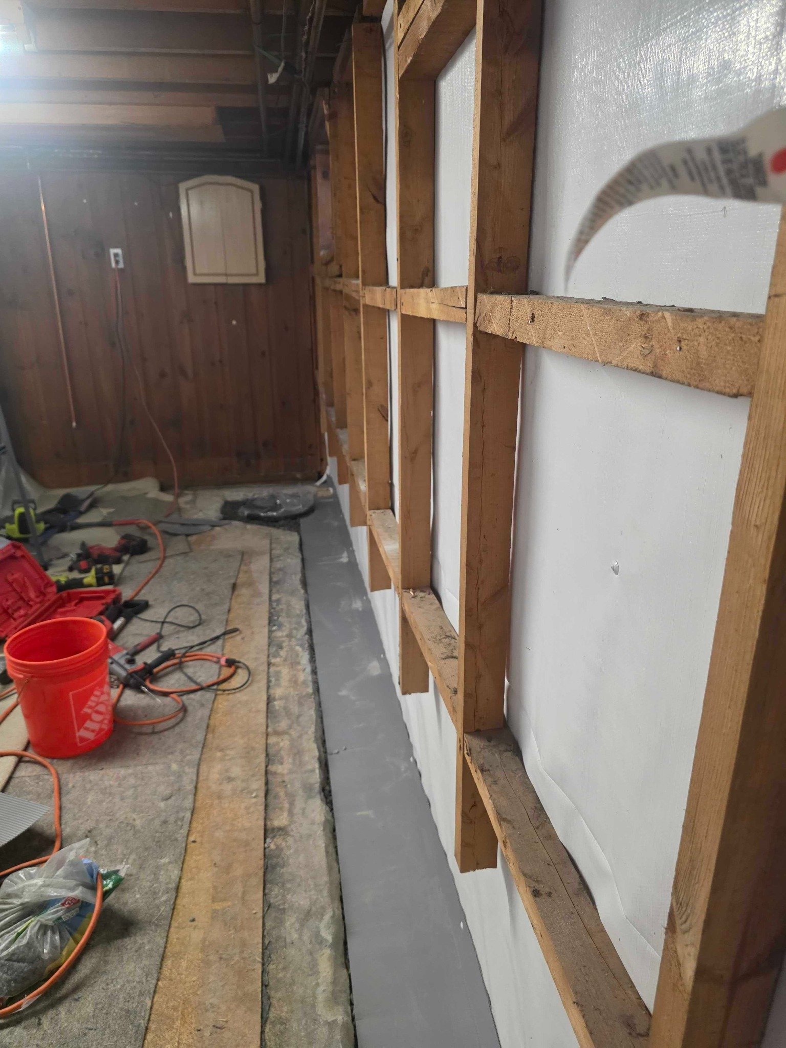 Drainage trench work with exposed framing and installation tools in the Manchester basement.