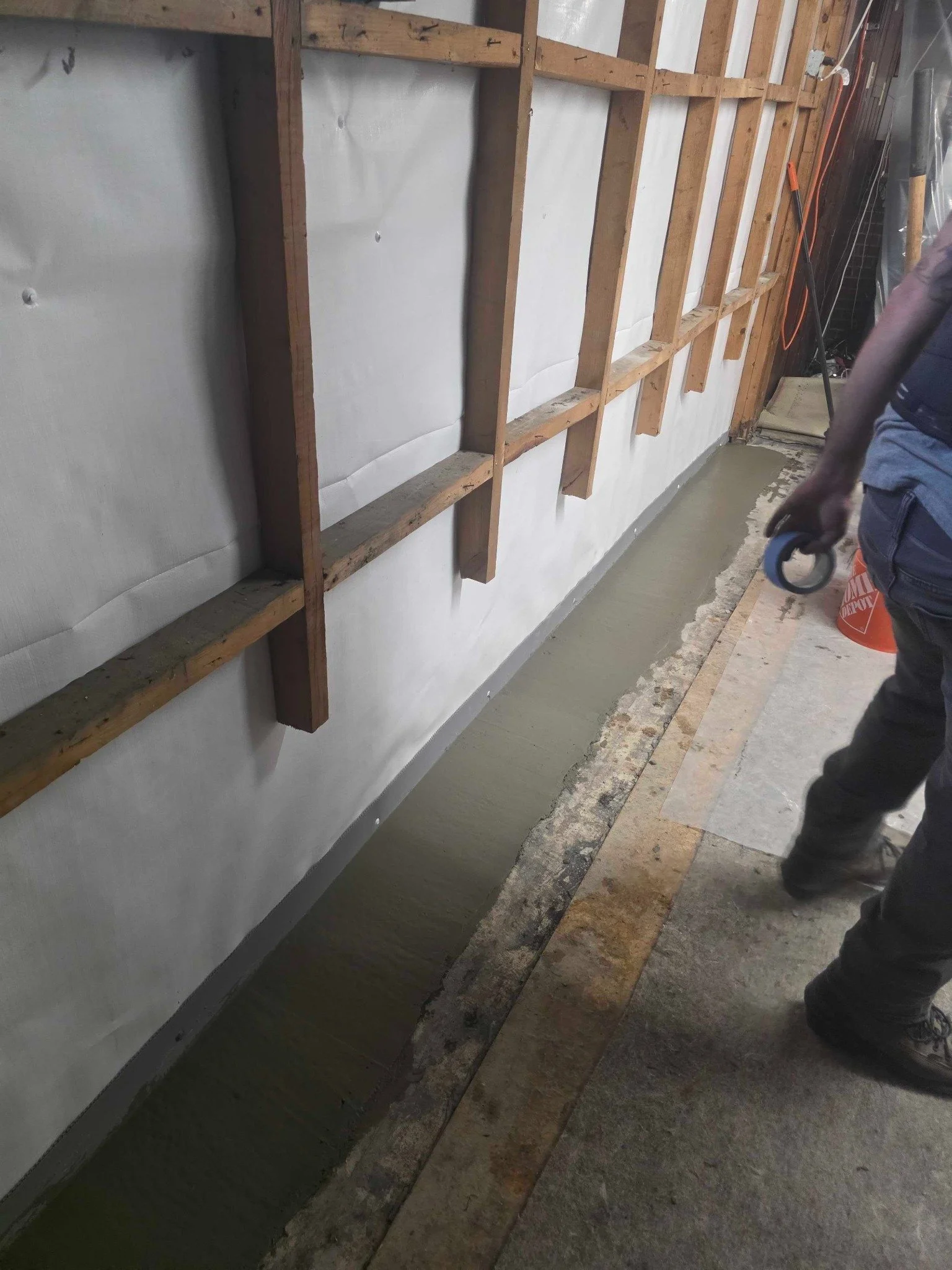 Basement drainage trench and exposed framing during waterproofing work in Manchester, New Hampshire.