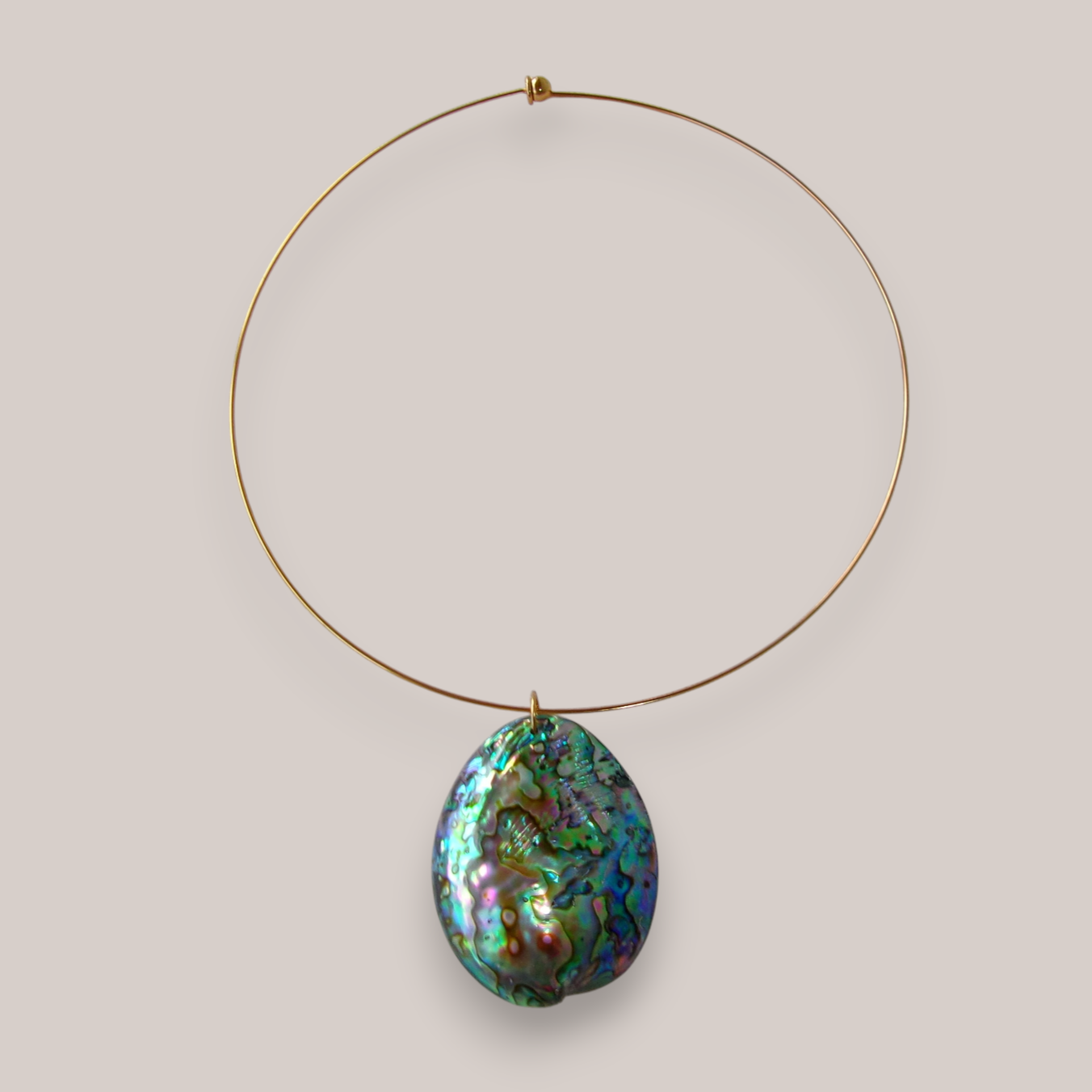 Gold wire necklace with large, oval-shaped, iridescent abalone shell pendant.