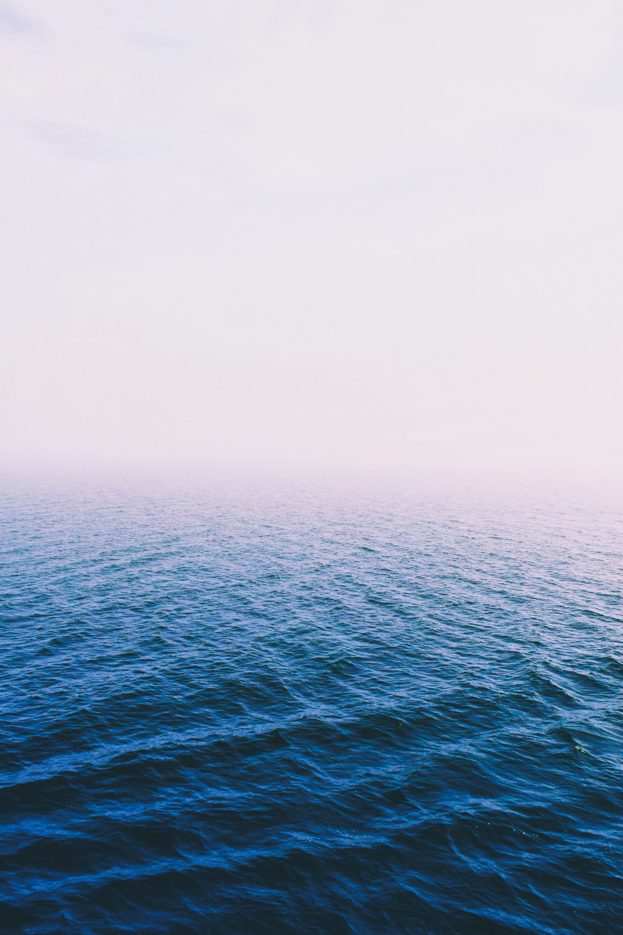 Ocean water with choppy waves, blue in color, under a light gray sky.