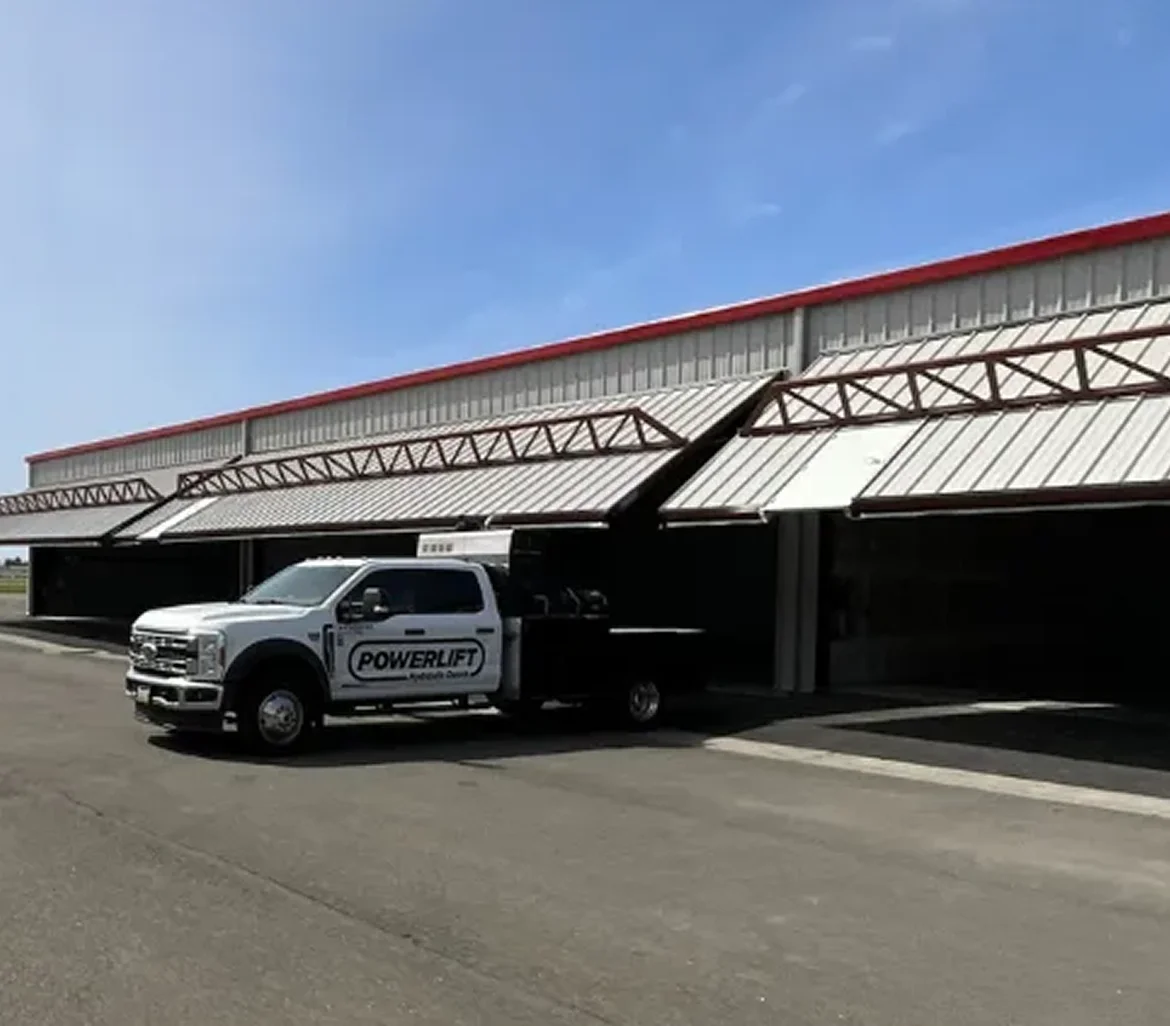 Aircraft hangar with a PowerLift hydraulic door and PowerLift service truck outside.