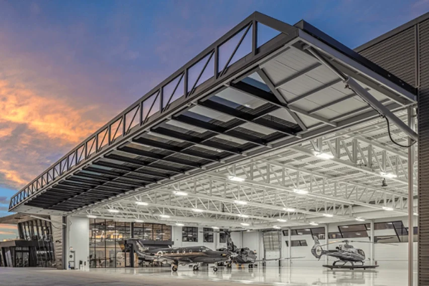 Aircraft hangar with large hydraulic door open inside a modern facility in California.
