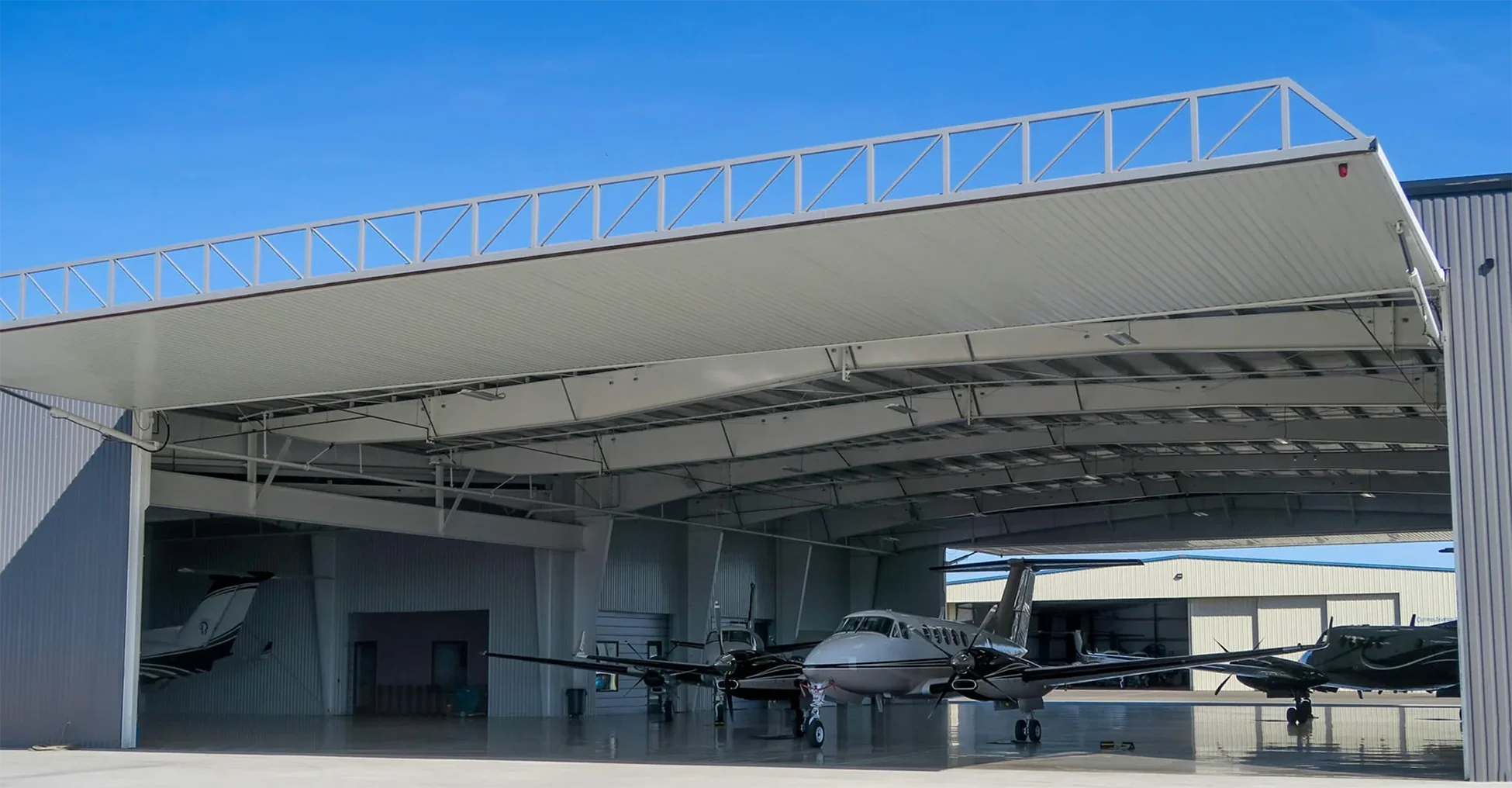 PowerLift hydraulic hangar door open on an aviation hangar with aircraft inside.