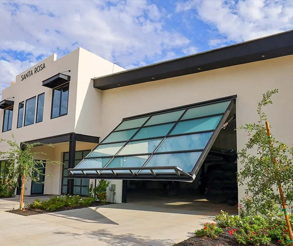 Modern building named Santa Rosa with a large, tilted glass garage door and surrounding landscaping.