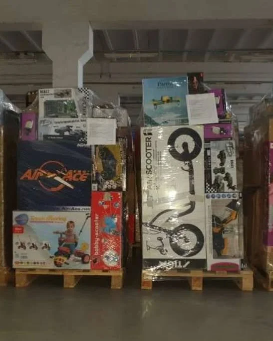 Pallets stacked with boxed toys and items in a warehouse.