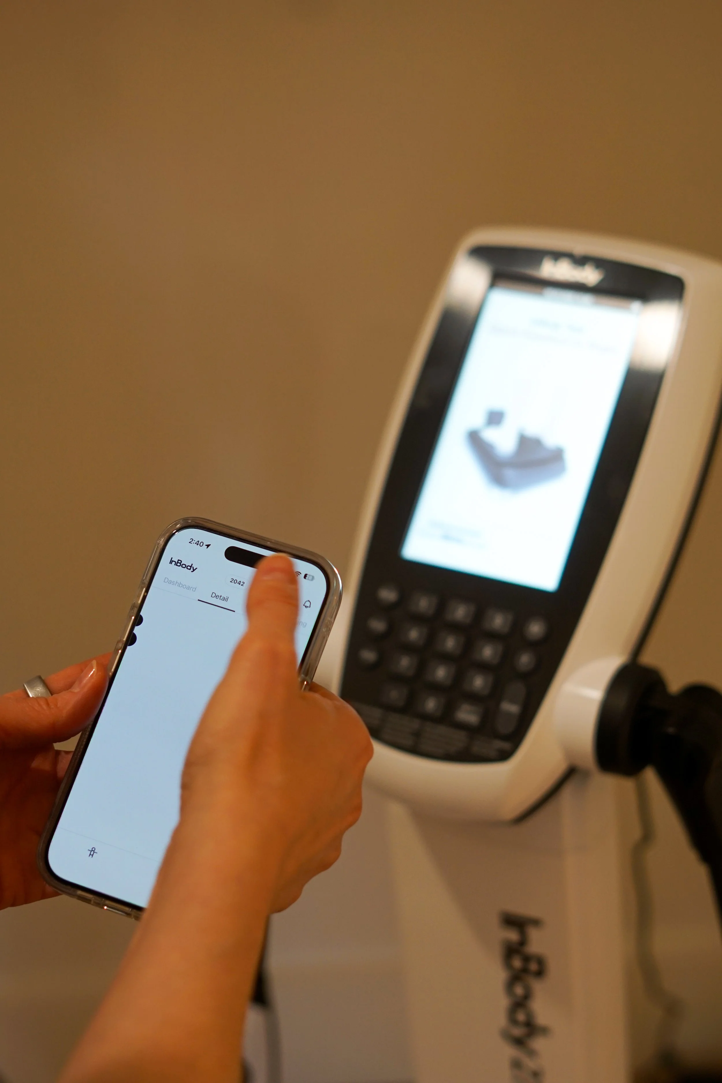 Person holding a smartphone using a fitness app near a medical scanner device.