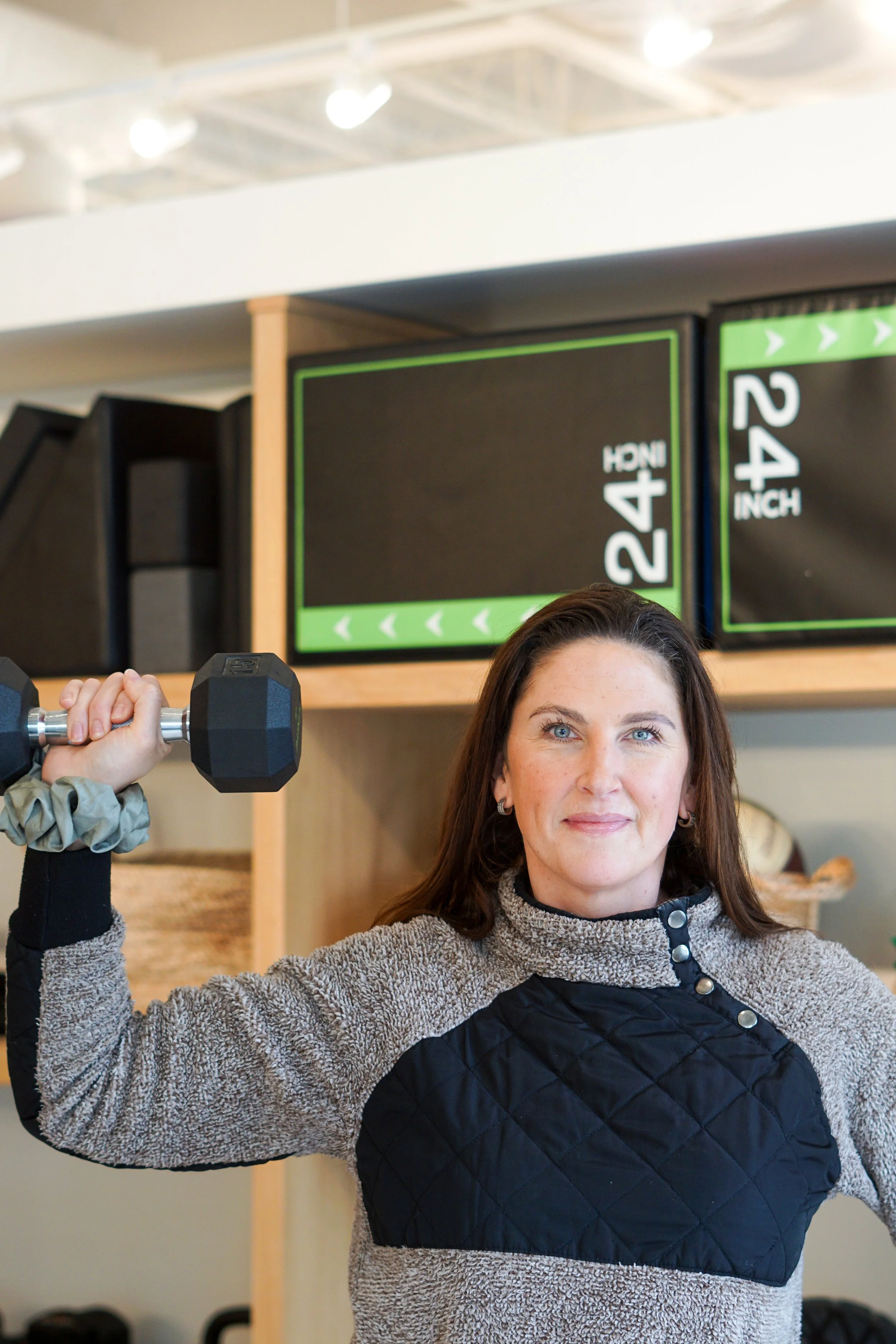 A woman lifting a dumbbell in a fitness studio.