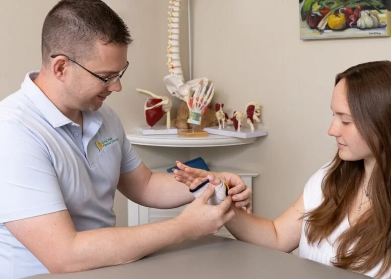 A physical therapist or doctor is examining a woman's arm, demonstrating a muscular or joint movement, in a medical or therapy setting.