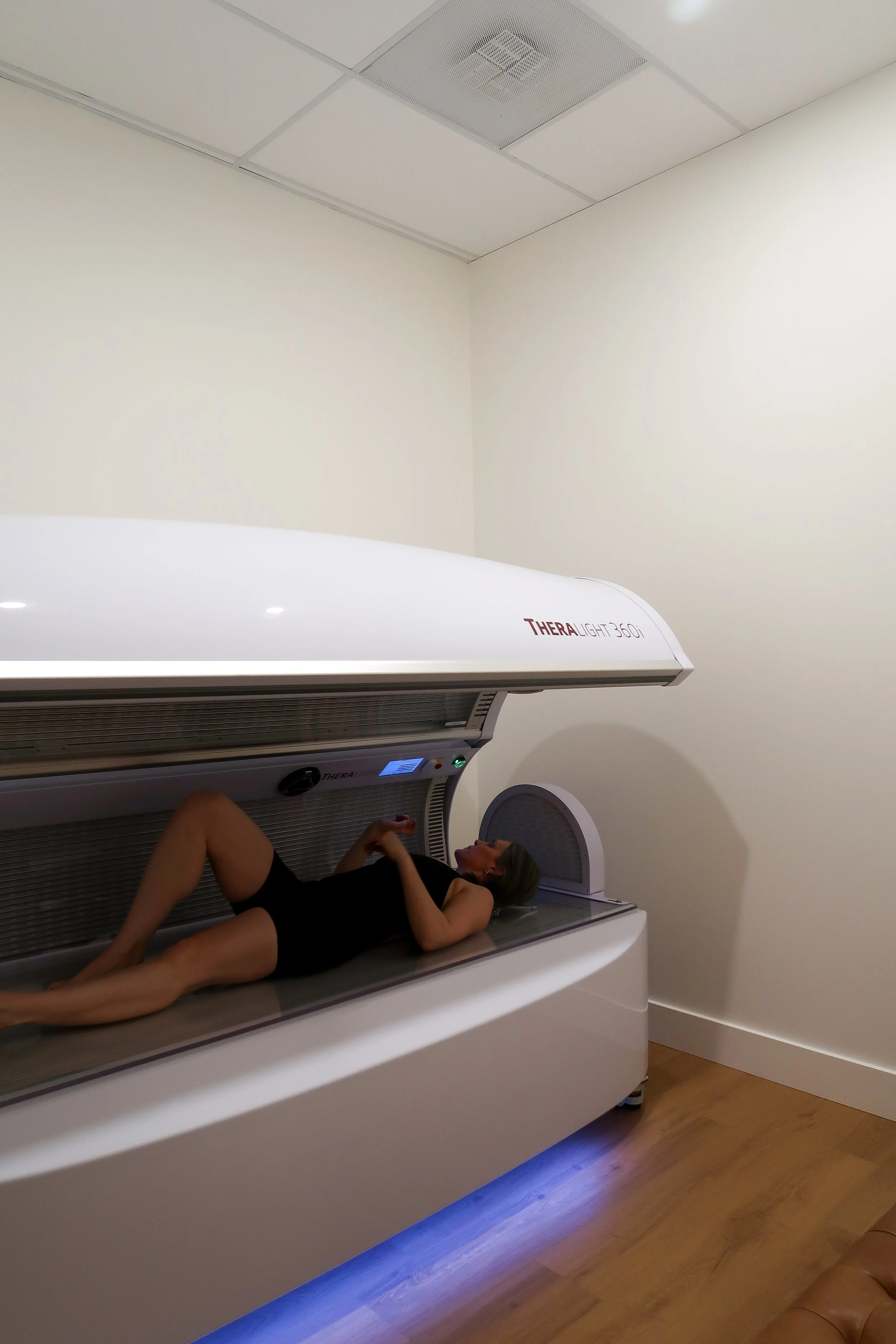 Person lying inside a large medical grade red light therapy bed in a private room.