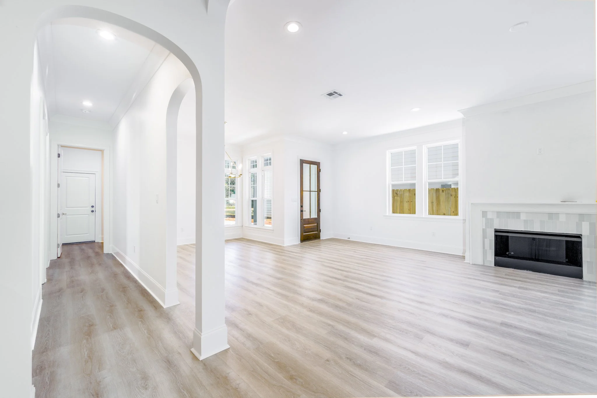 Bright, spacious living room with white walls, large windows, and a gas fireplace with a tile surround.