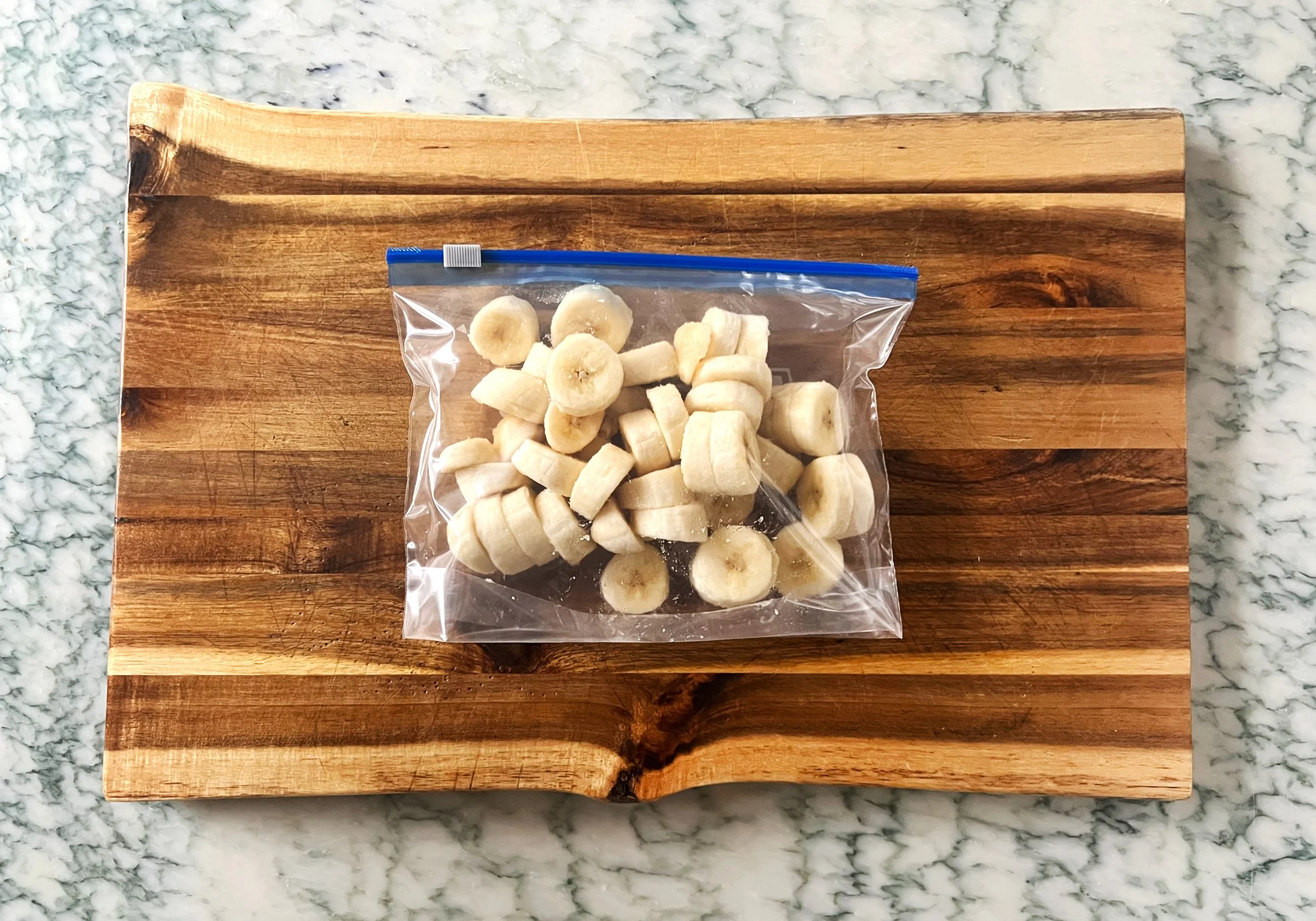 chopped bananas in a freezer safe bag on a cutting board