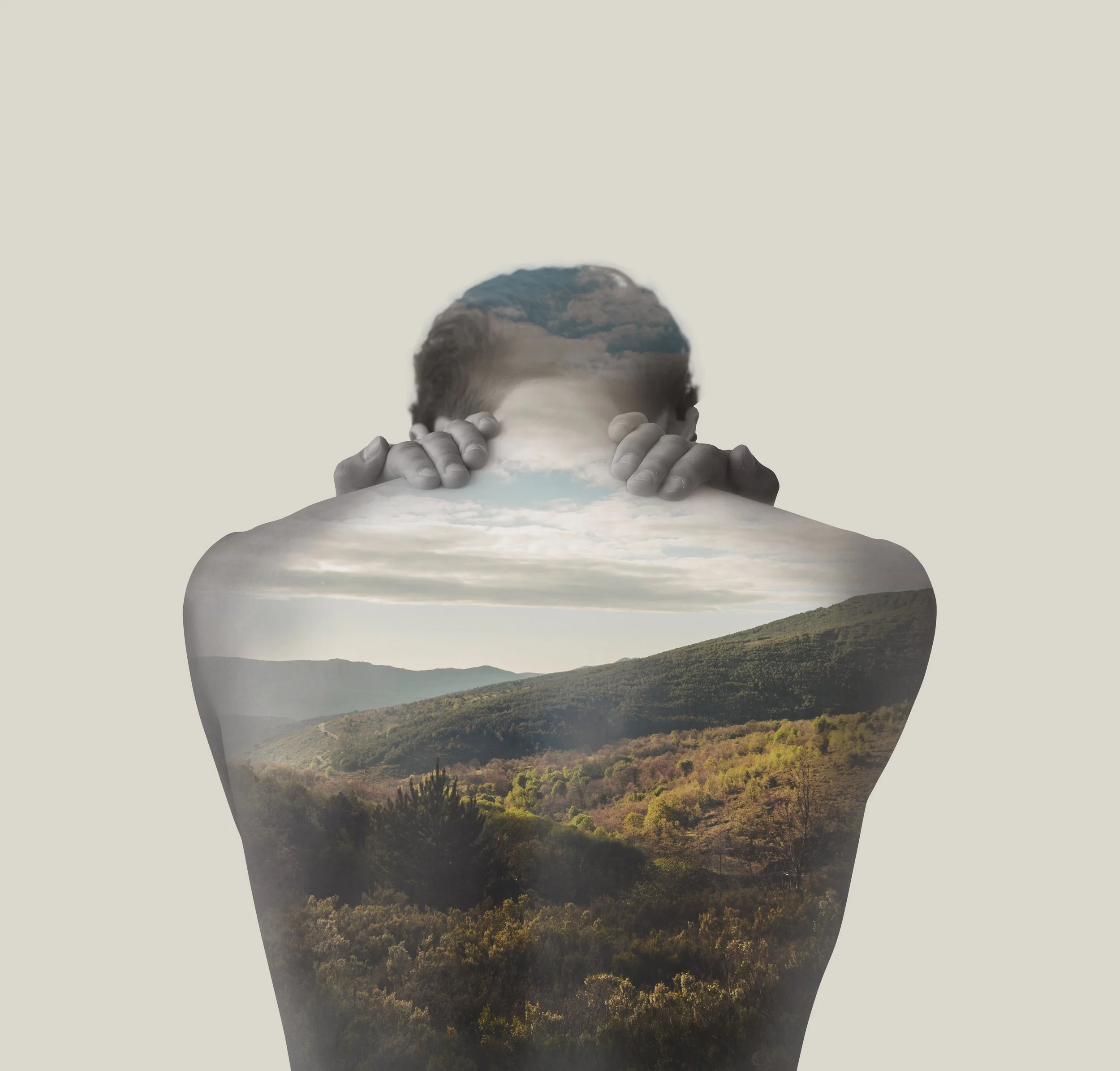 Double exposure image combining a person's head and hands with a landscape of mountains and trees.