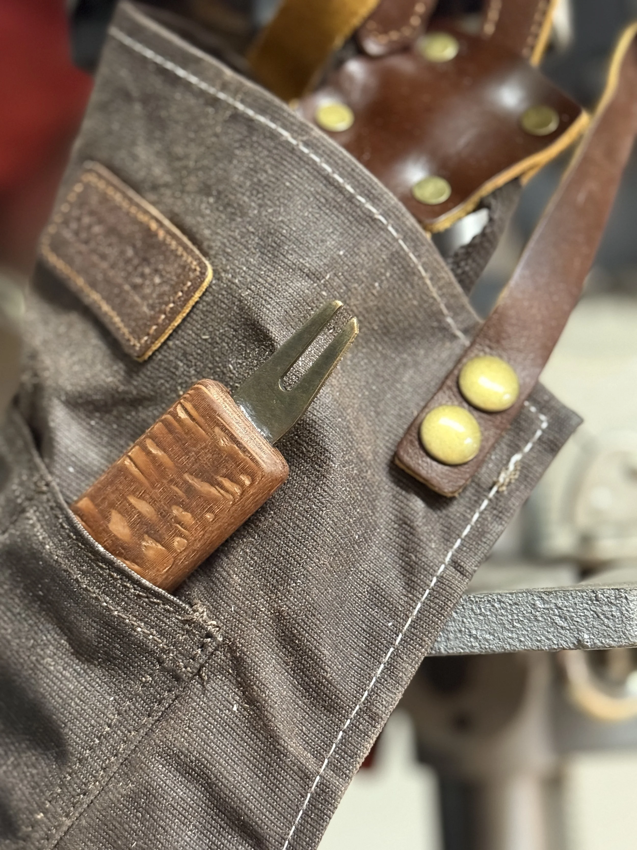 The Divsmith's apron with leopardwood golf divot tool in workshop — handcrafted in the USA