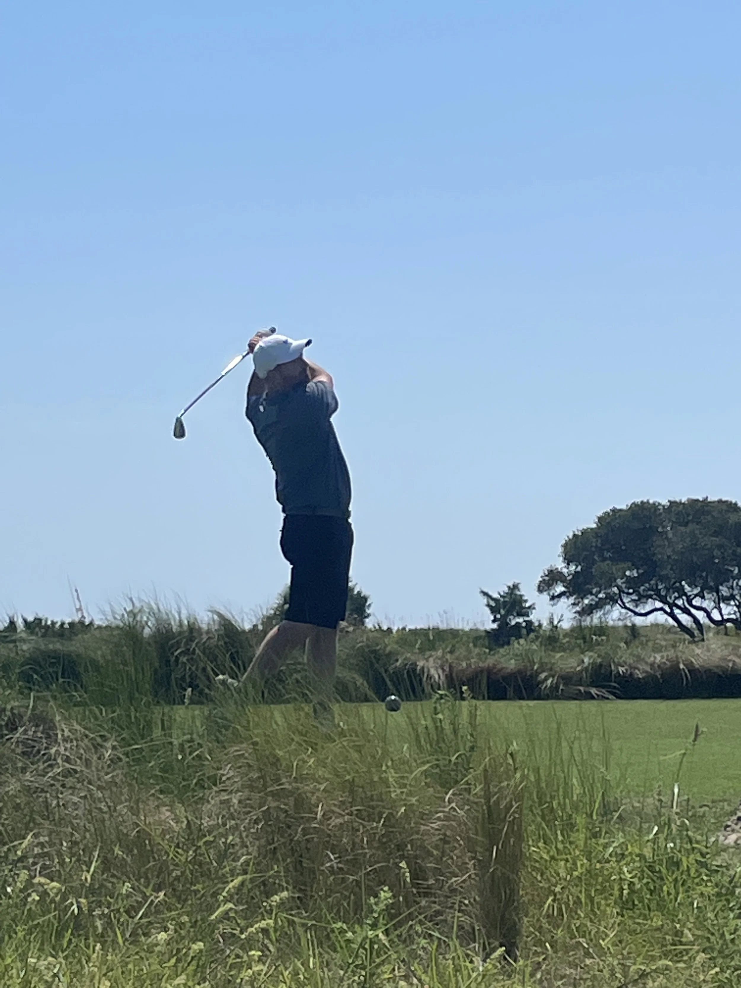 The Divsmith founder Nathan hitting a tee shot at a scenic oceanside golf course — a lifelong love of the game continues.