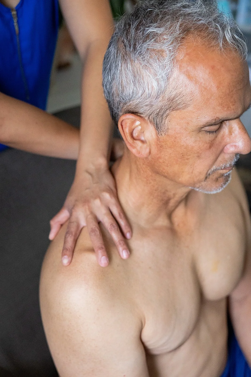 Shift Mind Body Spirit_Myofascial Release Therapy_Berkeley, CA_A man getting a shoulder massage from a therapist, with the man's eyes closed and a peaceful expression.