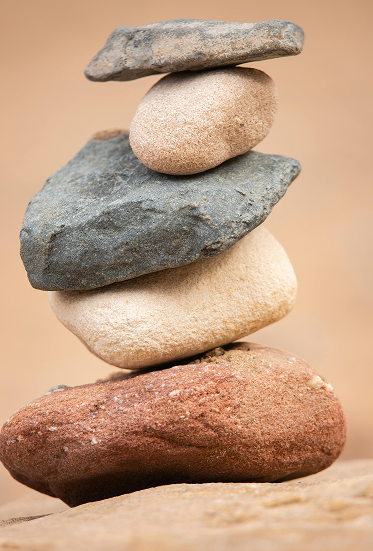 Shift Mind Body Spirit_Myofascial Release Therapy_Berkeley, CA_Stack of six balanced stones on a wooden surface with a neutral background.