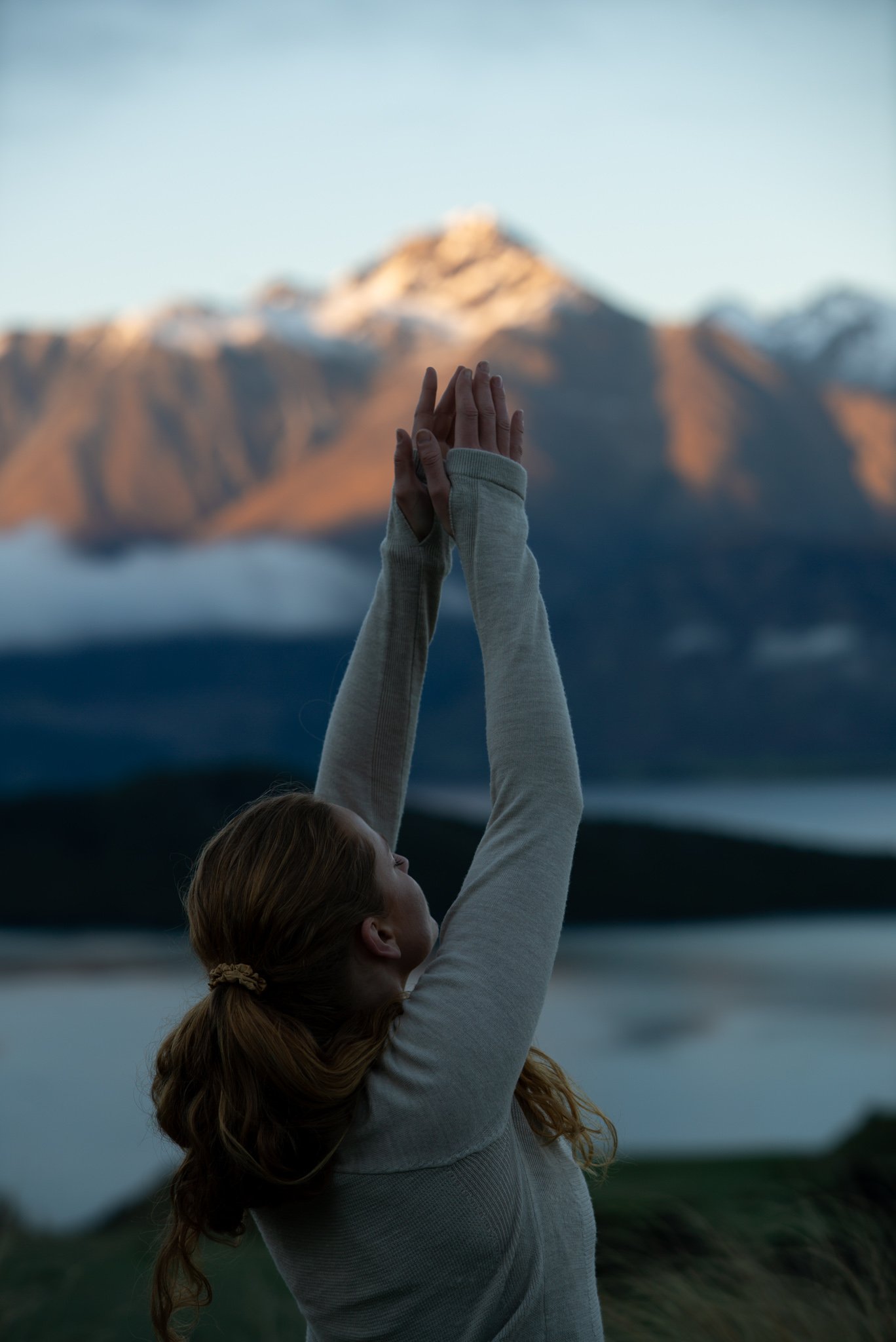 Anna Chaparro reaching towards mountain at sunrise, Queenstown, New Zealand
