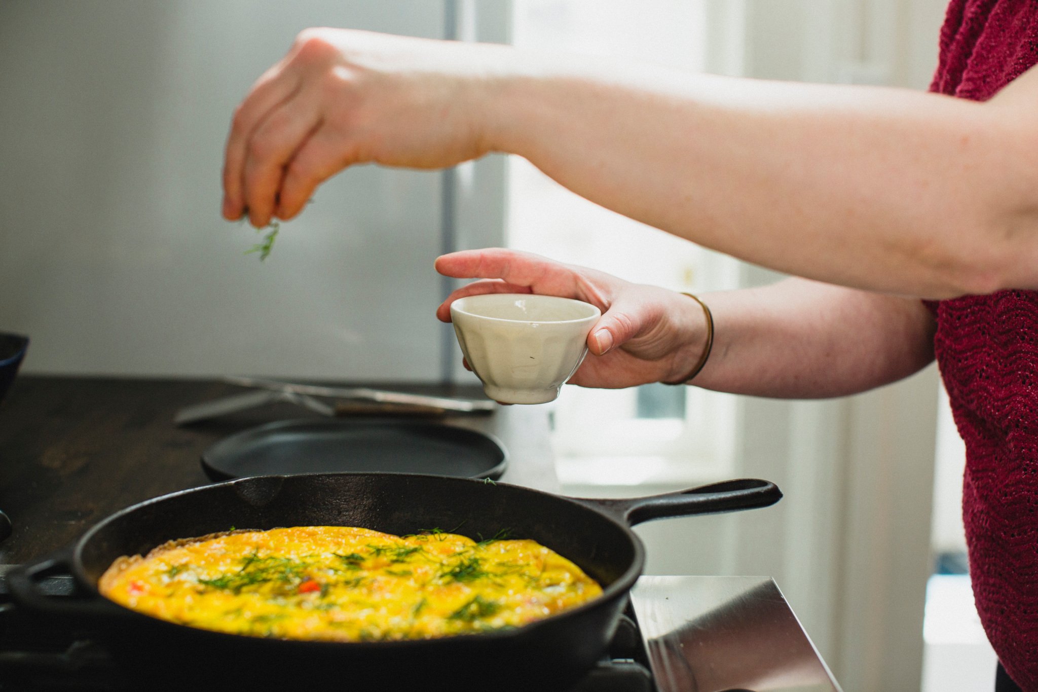 Host, Jen, preparing an egg bake over a stovetop in the kitchen.
