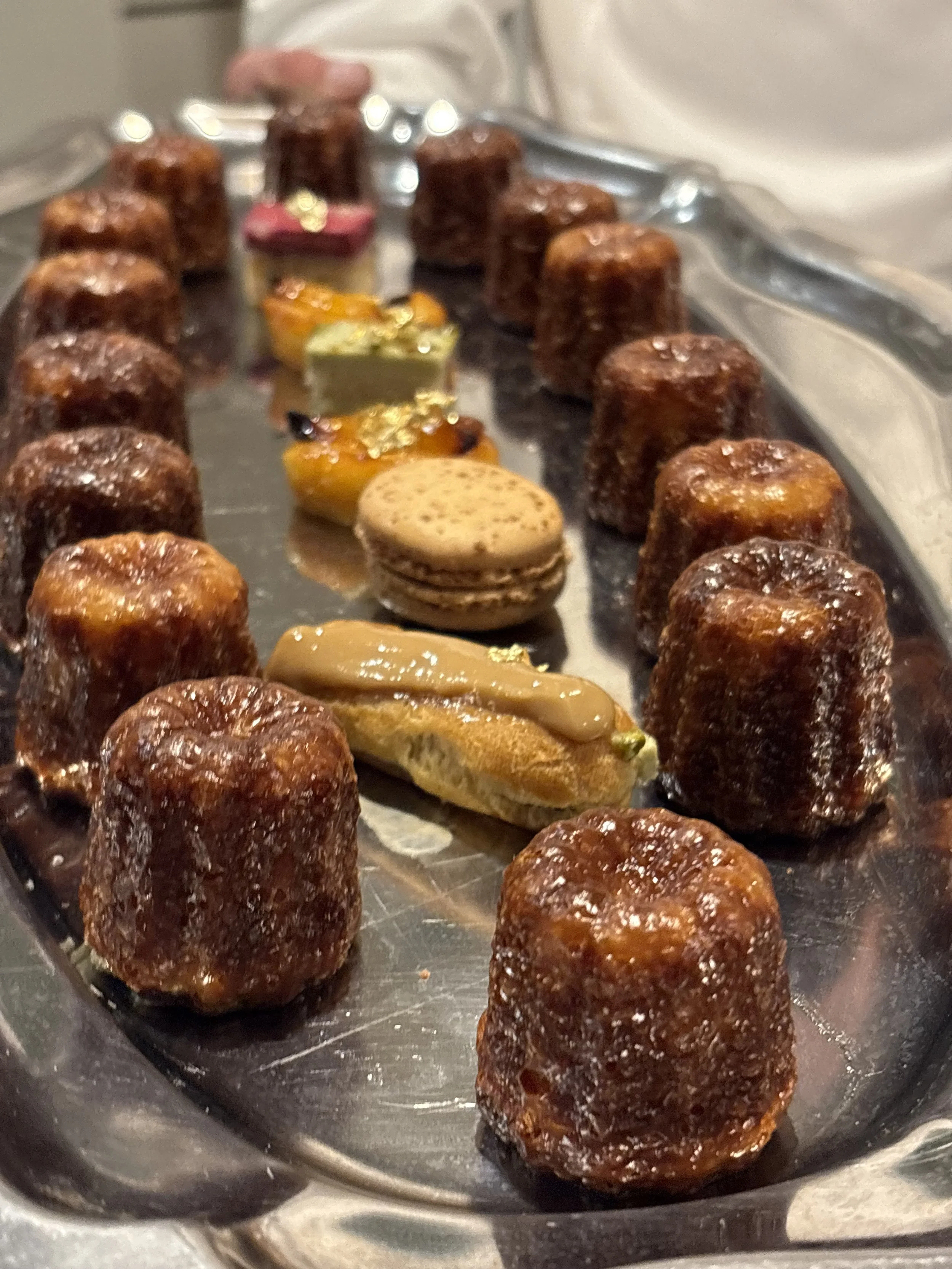 Gâteaux de chocolat avec des décorations en macarons, éclairs et fruits, présentés sur un plateau en métal.