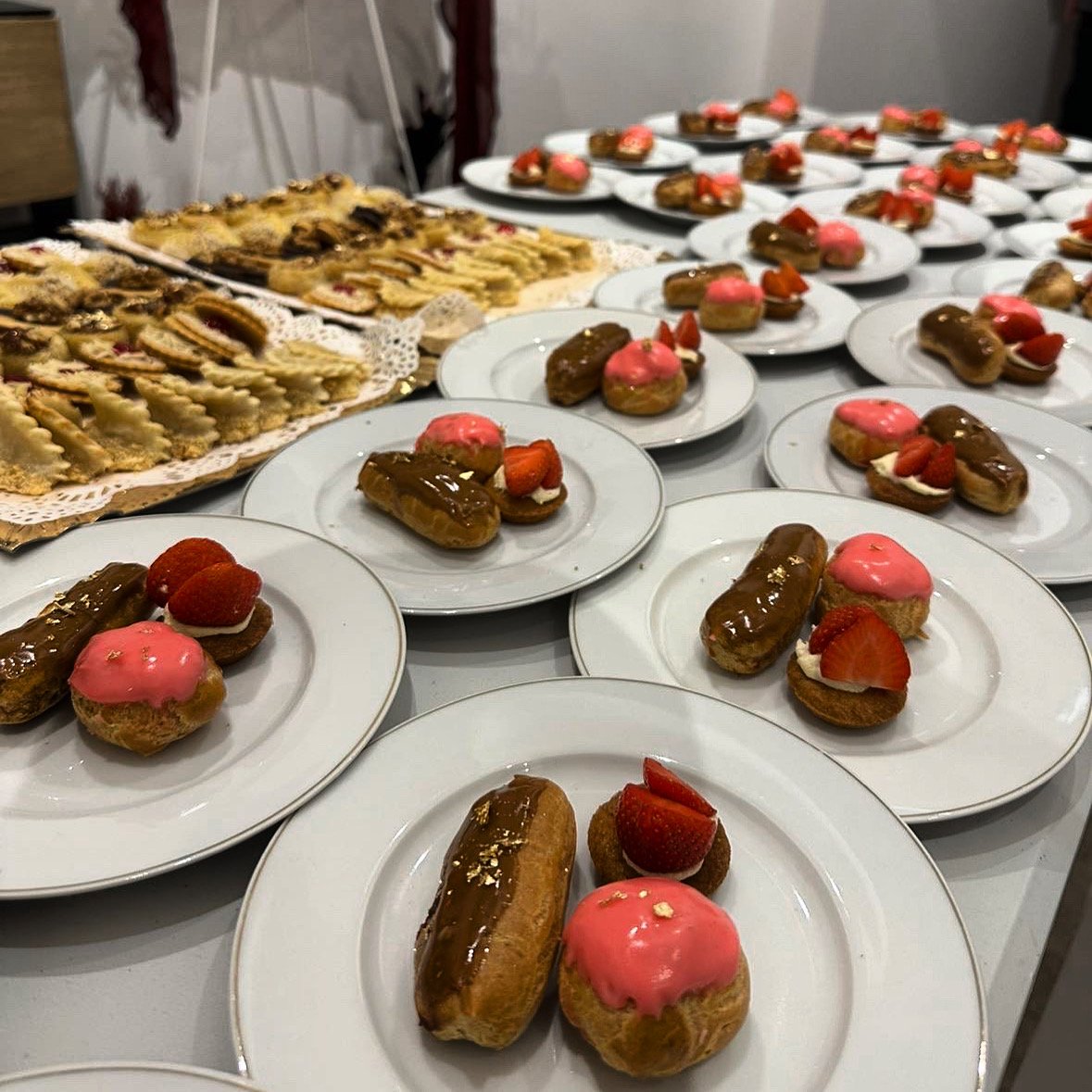 Plateaux de desserts, incluant éclairs au chocolat, éclairs à la fraise, et biscuits aux fraises, pour un événement festif.