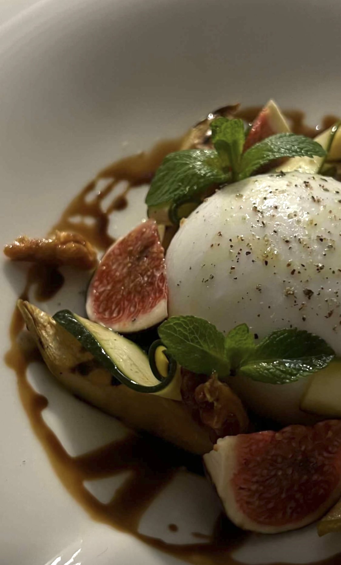 Œuf poché sur un lit de légumes, figues, citron vert, sauce, garnitures de menthe, avec assaisonnement.